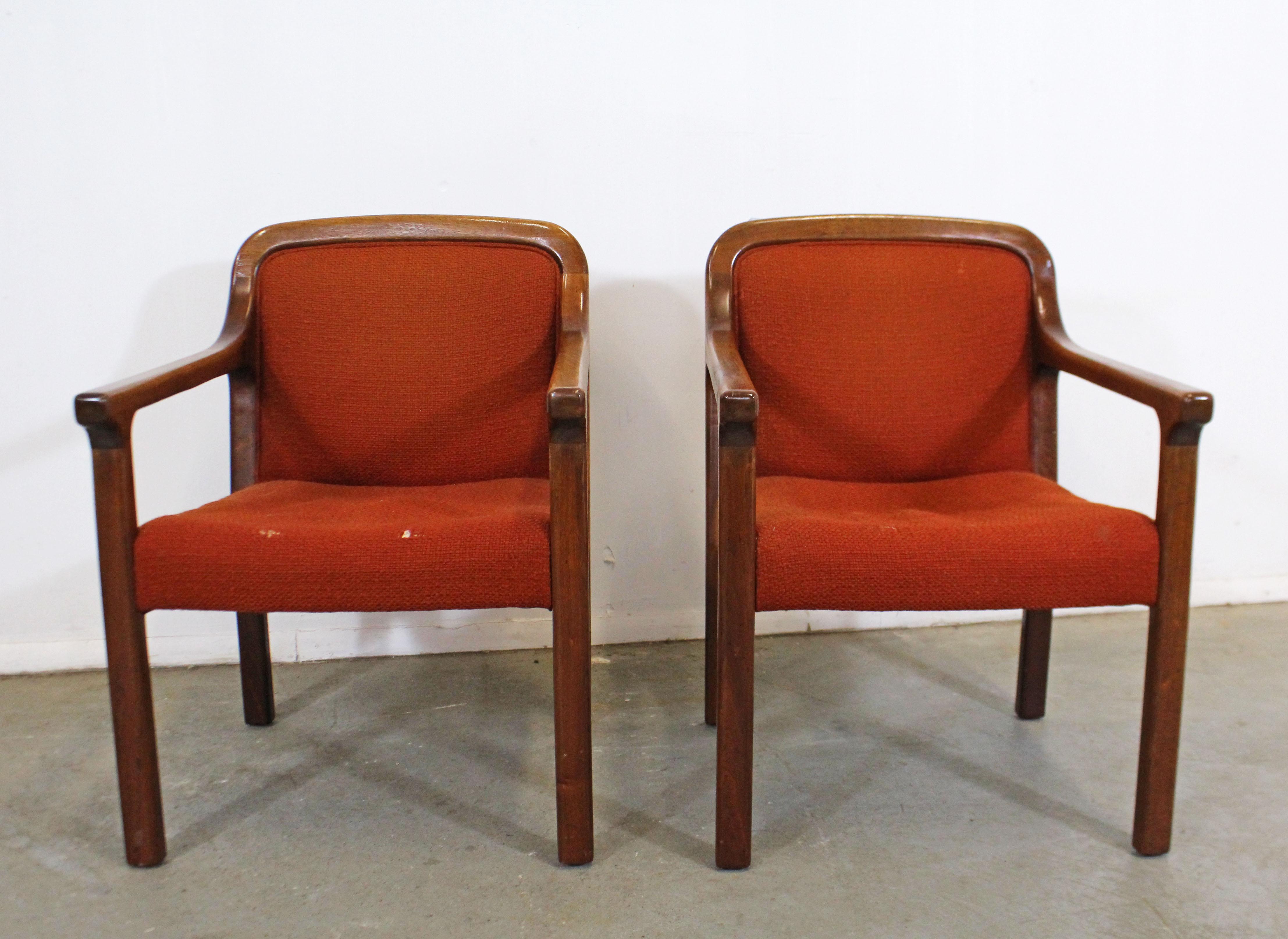 Offered is a pair of vintage Mid-Century Modern style walnut armchairs (circa 1970s). With fine lines and a beautiful wood grain, these chairs are perfect for any space or design project. Make them your own! Features walnut bases and upholstered