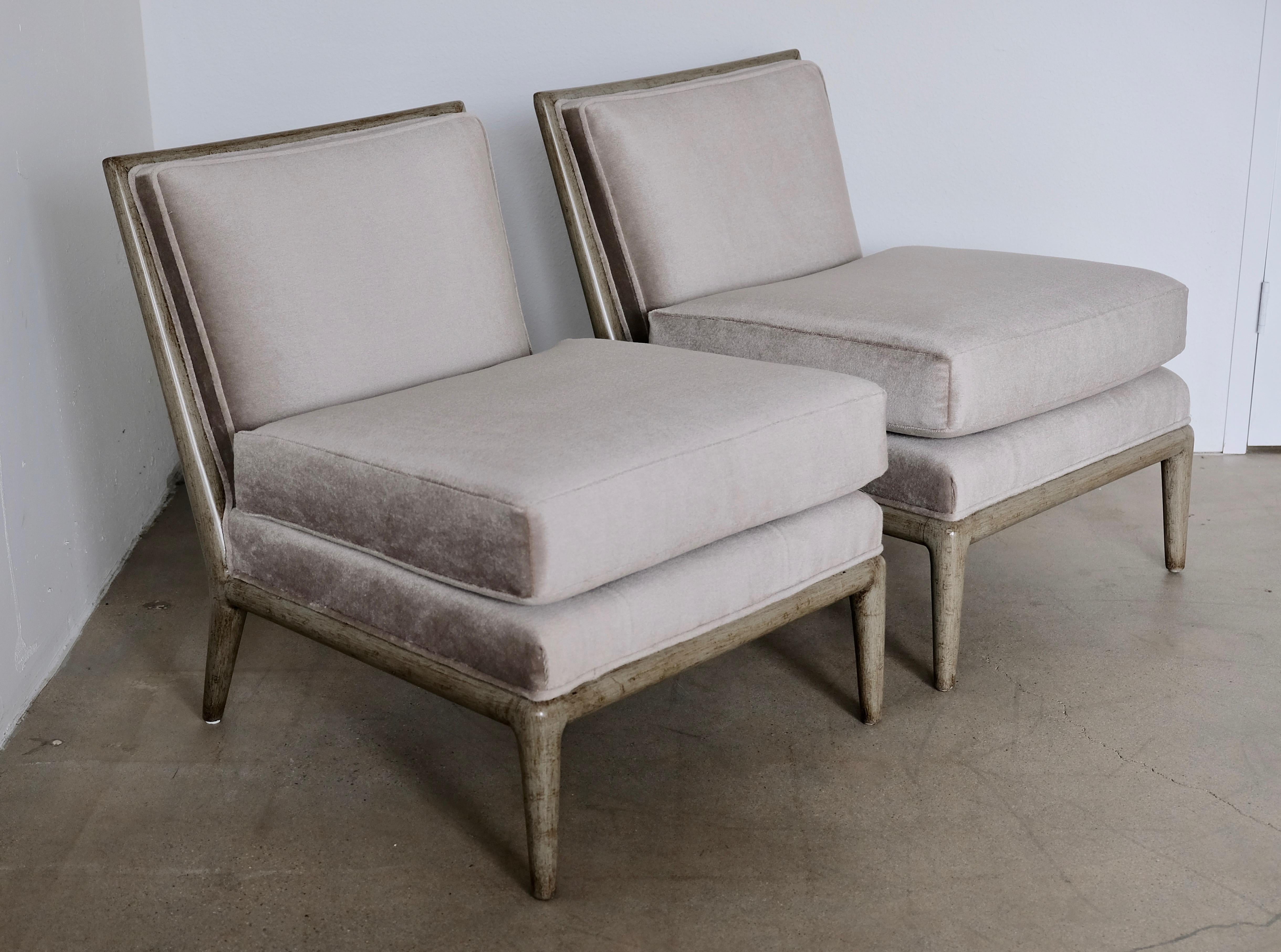 A pair of vintage Mid-Century Modern slipper chairs in the style of Paul McCobb and T.H. Robsjohn Gibbings. The chairs have been recovered in a silver grey mohair fabric. The base has an antiqued grey finish. The top seat cushion is removable and