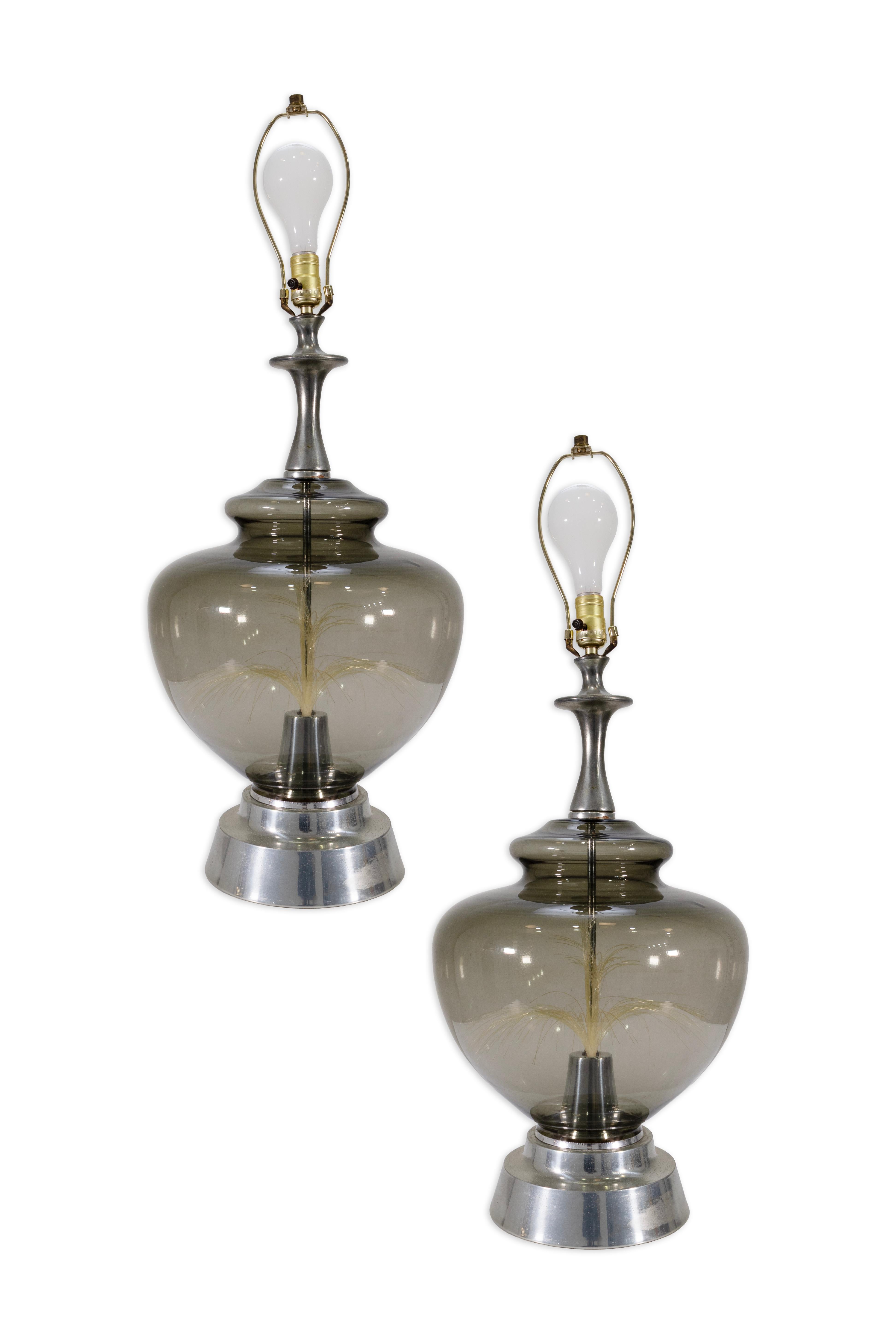 Un mix sorprendente di design retro-futuristico e stile di metà secolo, questa coppia di lampade rotonde in vetro fumé presenta un display interno in fibra ottica. Ogni lampada è realizzata con un corpo bulboso in vetro fumé appoggiato su una base