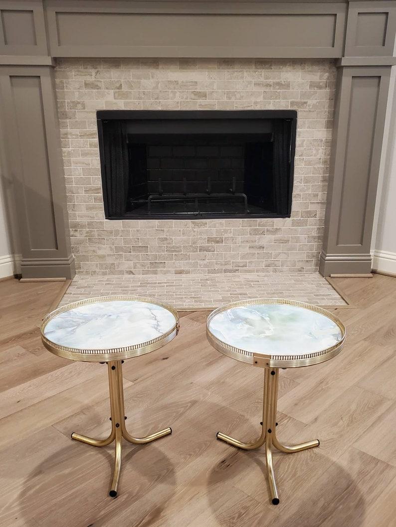 A scarce pair of Mid-Century Modern chrome drinks tables. Likely French in origin, the charming petite retro tables having a circular silver-tone pierced gallery raised rim, surrounding faux exotic marble sky blue painted wooden top, over a