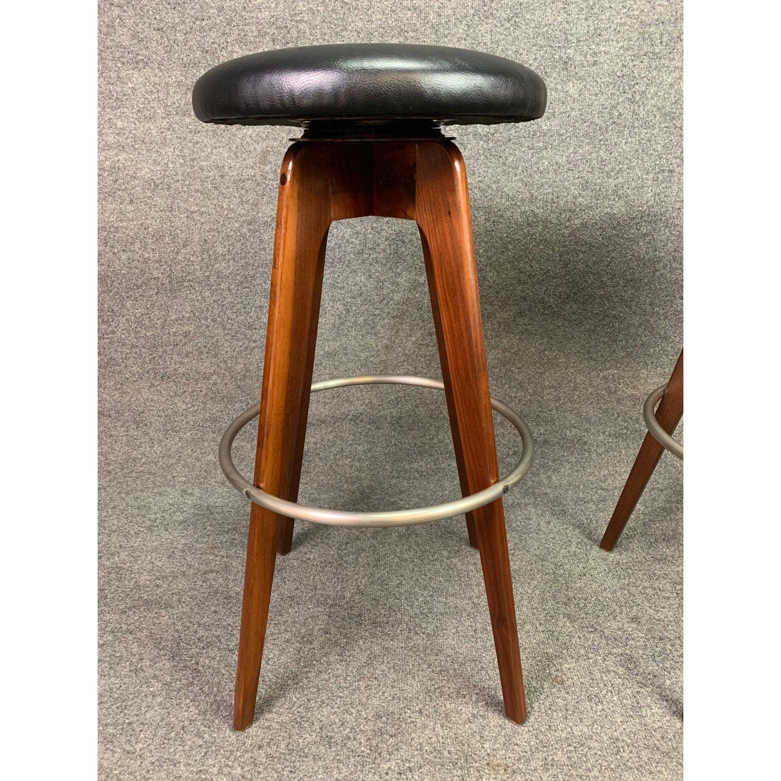 Here is a beautiful pair of Mid-Century Modern bar stools in walnut designed by Chet Beardsley and produced by Living Design in the US in the 1960s.
These fully restored stools feature a solid American black walnut frame, a polished metal circled