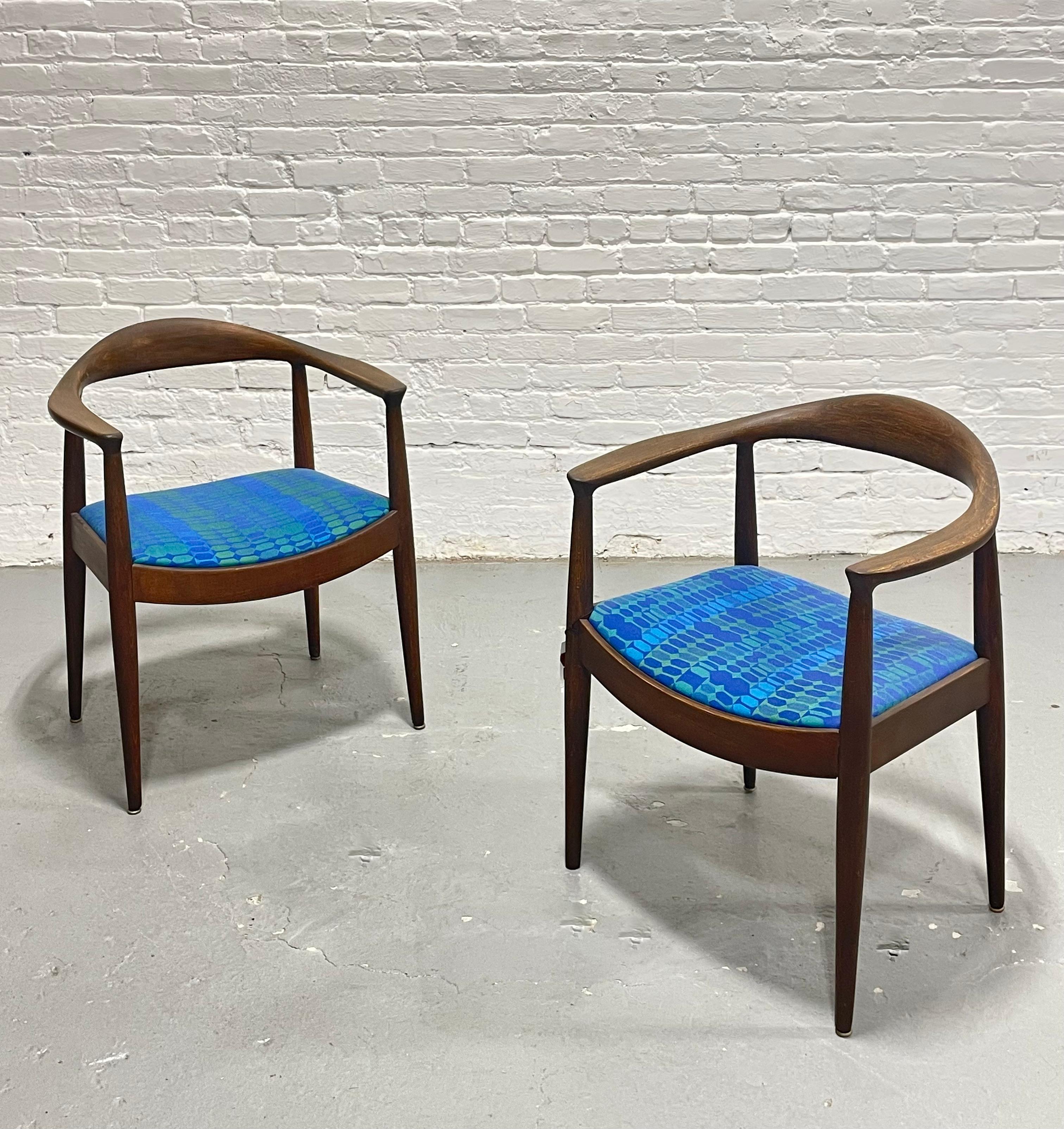 Pair of vintage Mid Century Modern lounge chairs in the style of Hans Wegner, crafted with elegant curvilinear solid walnut frames. The wood has been expertly refinished to reveal its rich tones and striking natural grain. Each chair is newly