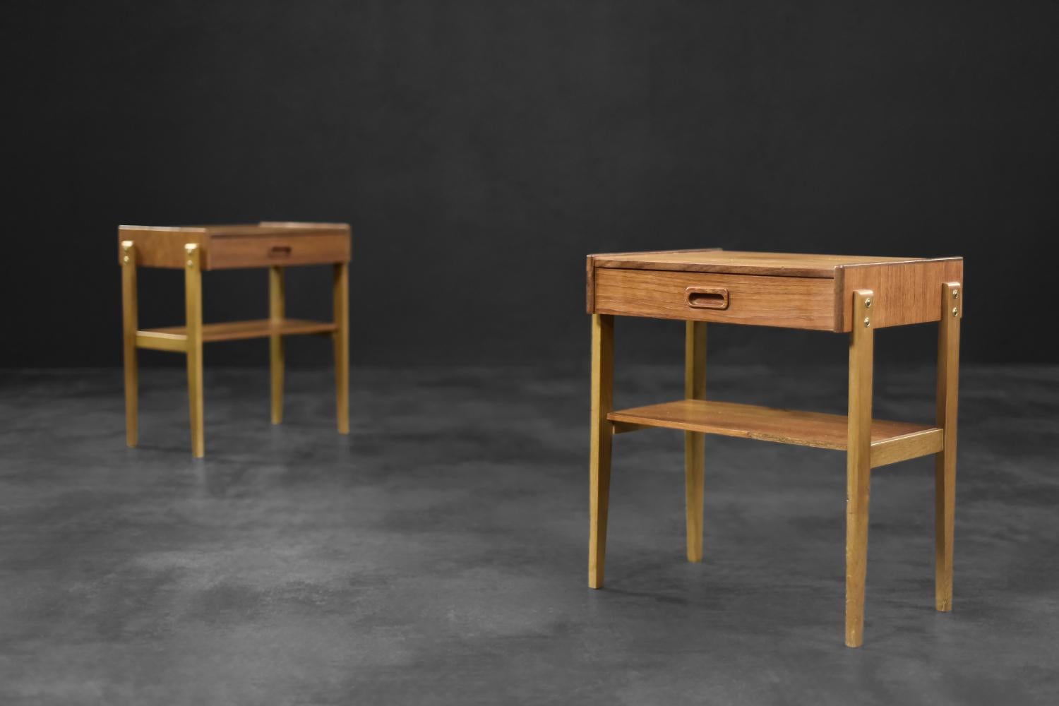 
This set of two bedside tables was made in Sweden during the 1960s. The pieces were finished with teak wood. They have a drawer and a handy shelf. The slender legs are made of solid wood and emphasize a delicate form of them. This set perfect match