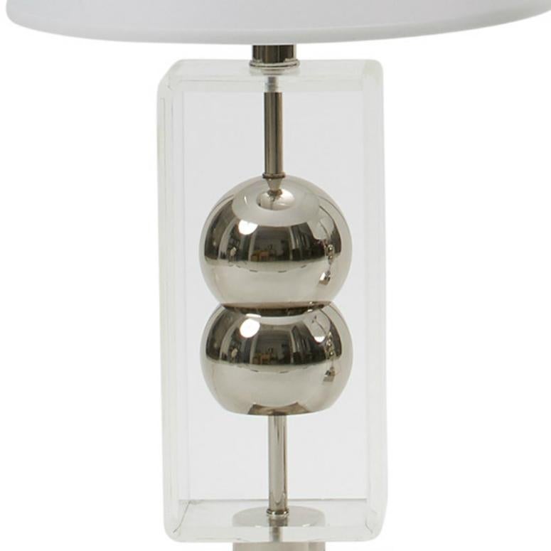 Unique chrome and Lucite lamps attributed to Laurel Studios. Two chrome orbs are suspended on the lamp’s main support, surrounded by a thick frame of curved Lucite. A chrome pedestal base reflects the lamp’s fashionable silhouette. 

Some minor