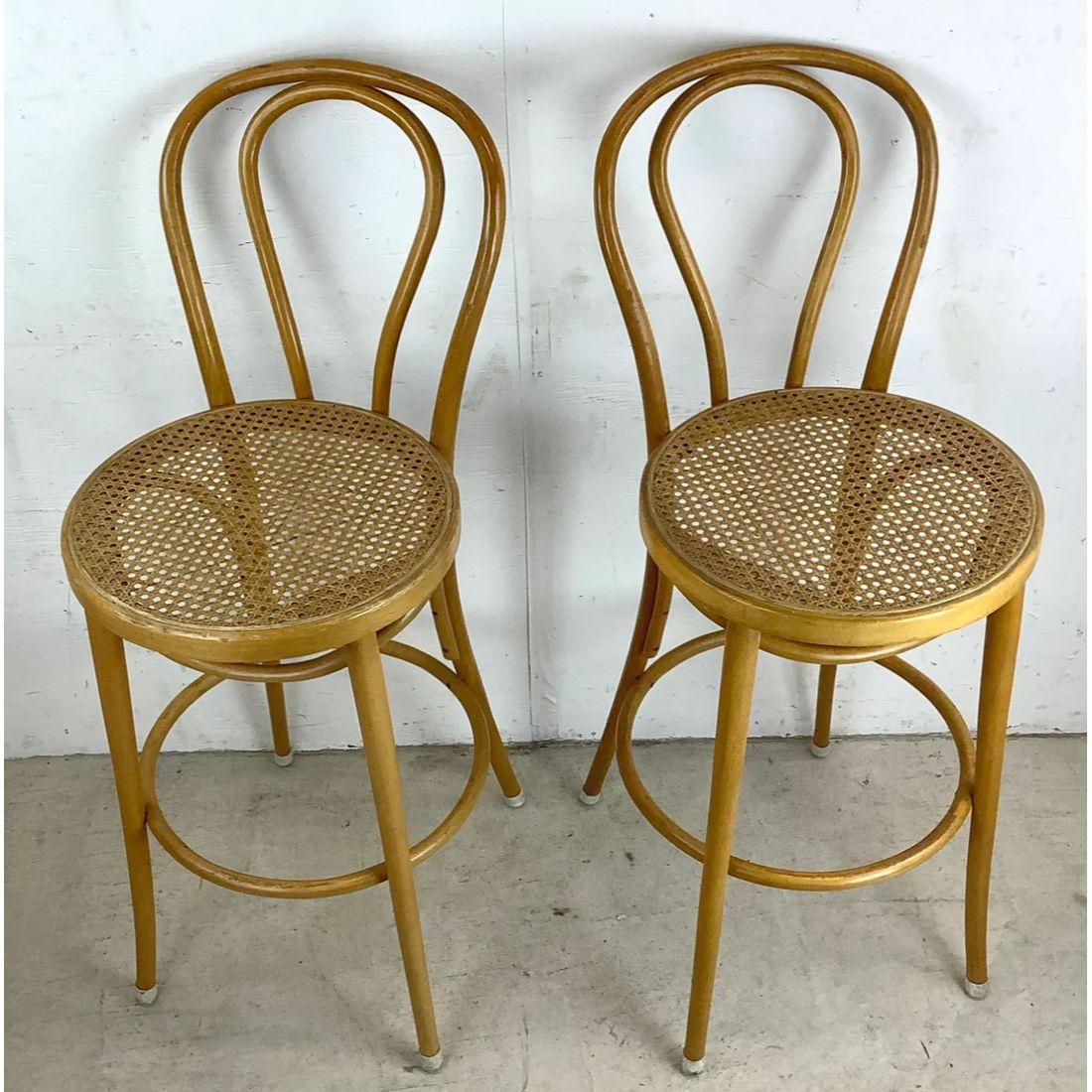 Enhance your home bar with a touch of vintage charm and modern elegance with this Pair of Vintage Modern Cane Seat Barstools, and Immerse yourself in the allure of mid-century design. The combination of the sleek wooden frames and the classic cane