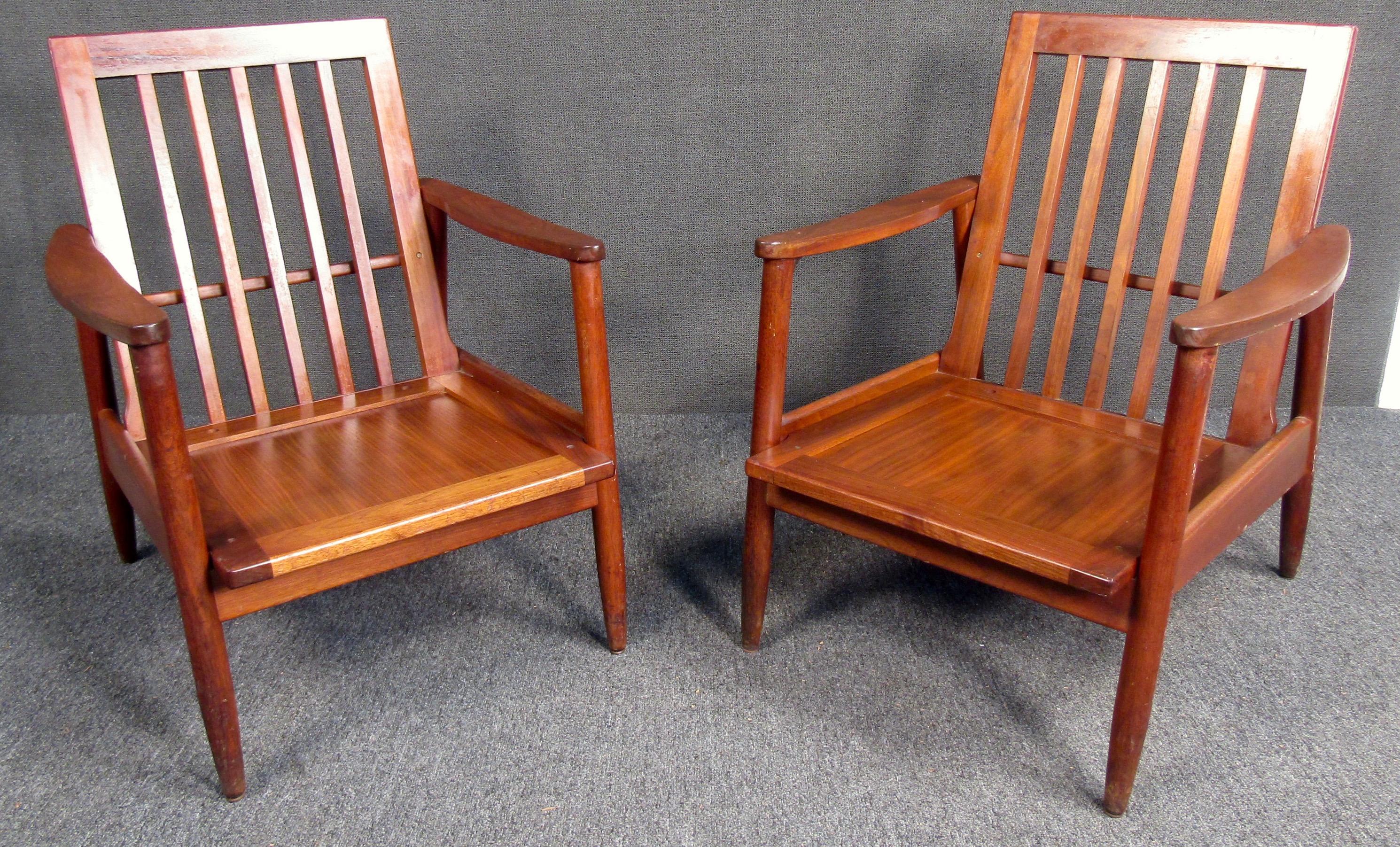 Stunning pair of Mid-Century Modern walnut chairs. Featuring rich walnut grain and a backrest set on a low-rise wooden frame with a light finish, the understated style and clean lines of this accent chair update your space with modern appeal.