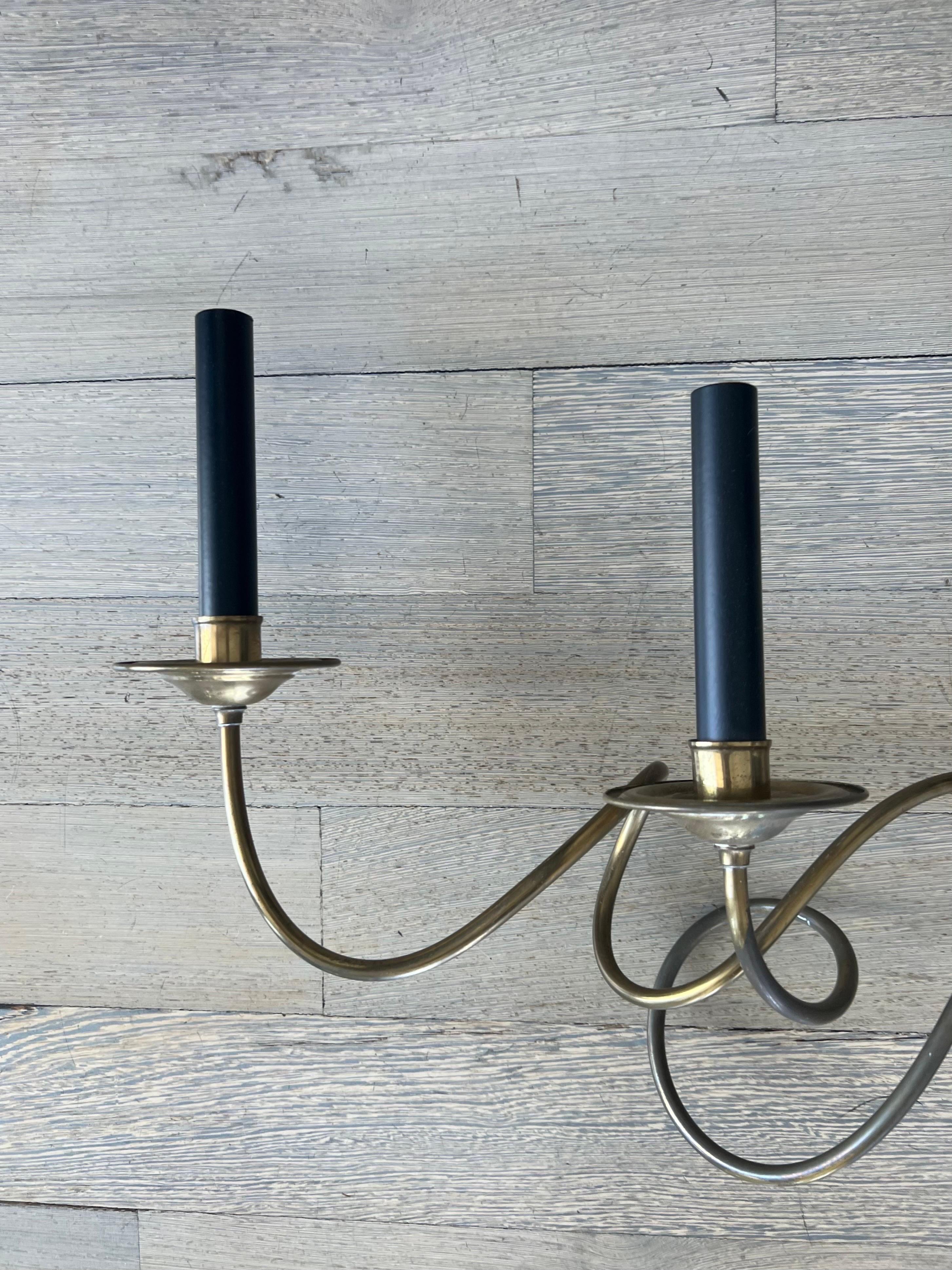 A pair of vintage, monumental-sized polished brass sconces, each having 6 curlicue-shaped arms with faux candlesticks and stylized gathered arrowhead base.  

USA, dating to 1920-1940.

Formerly from a residential installation project by famed