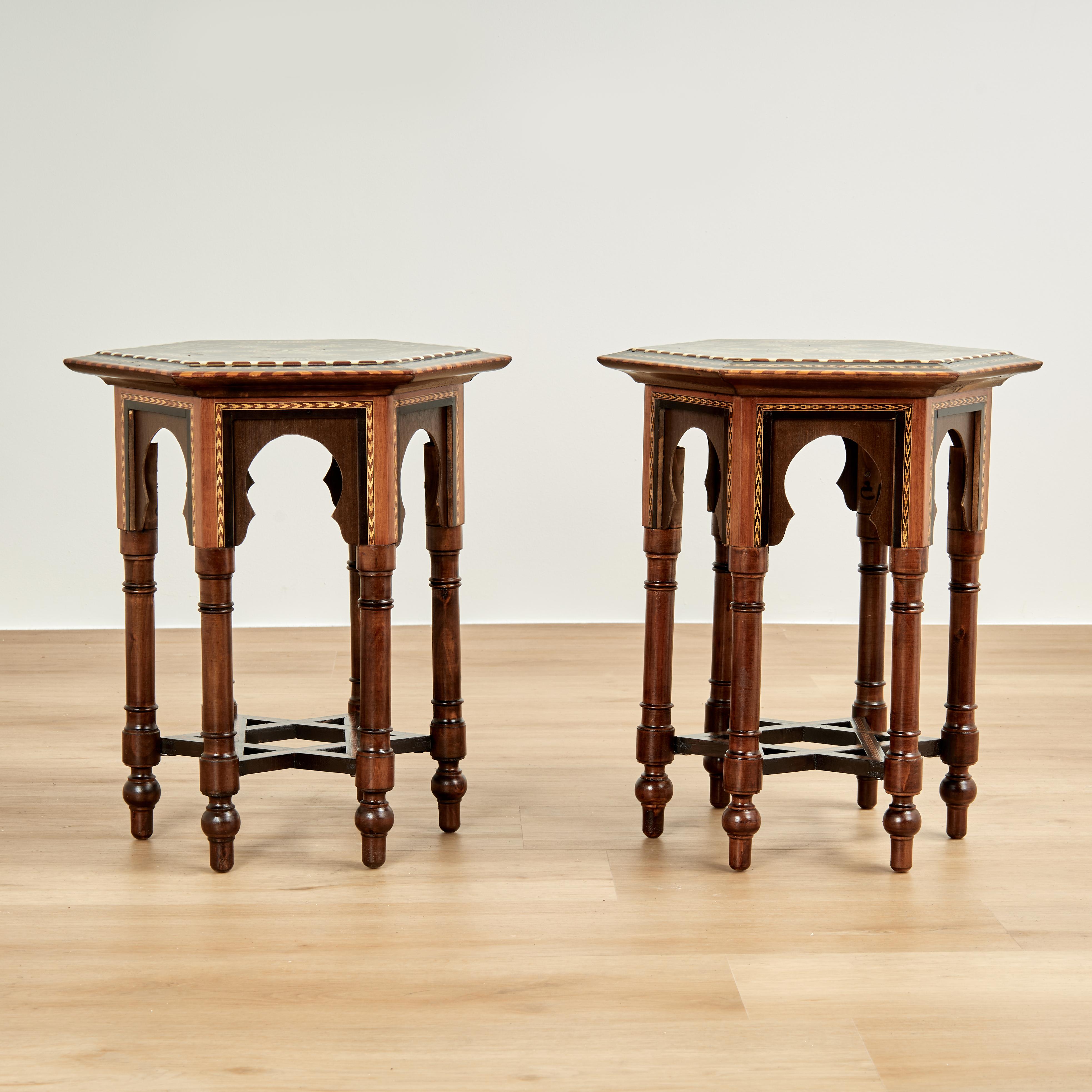 Impressive pair of vintage Moroccan stands crafted in walnut having hexagon tops decorated in elaborate inlays and marquetry of mahogany, ebony and bone in geometric designs on six turned legs joined by star form stretchers.