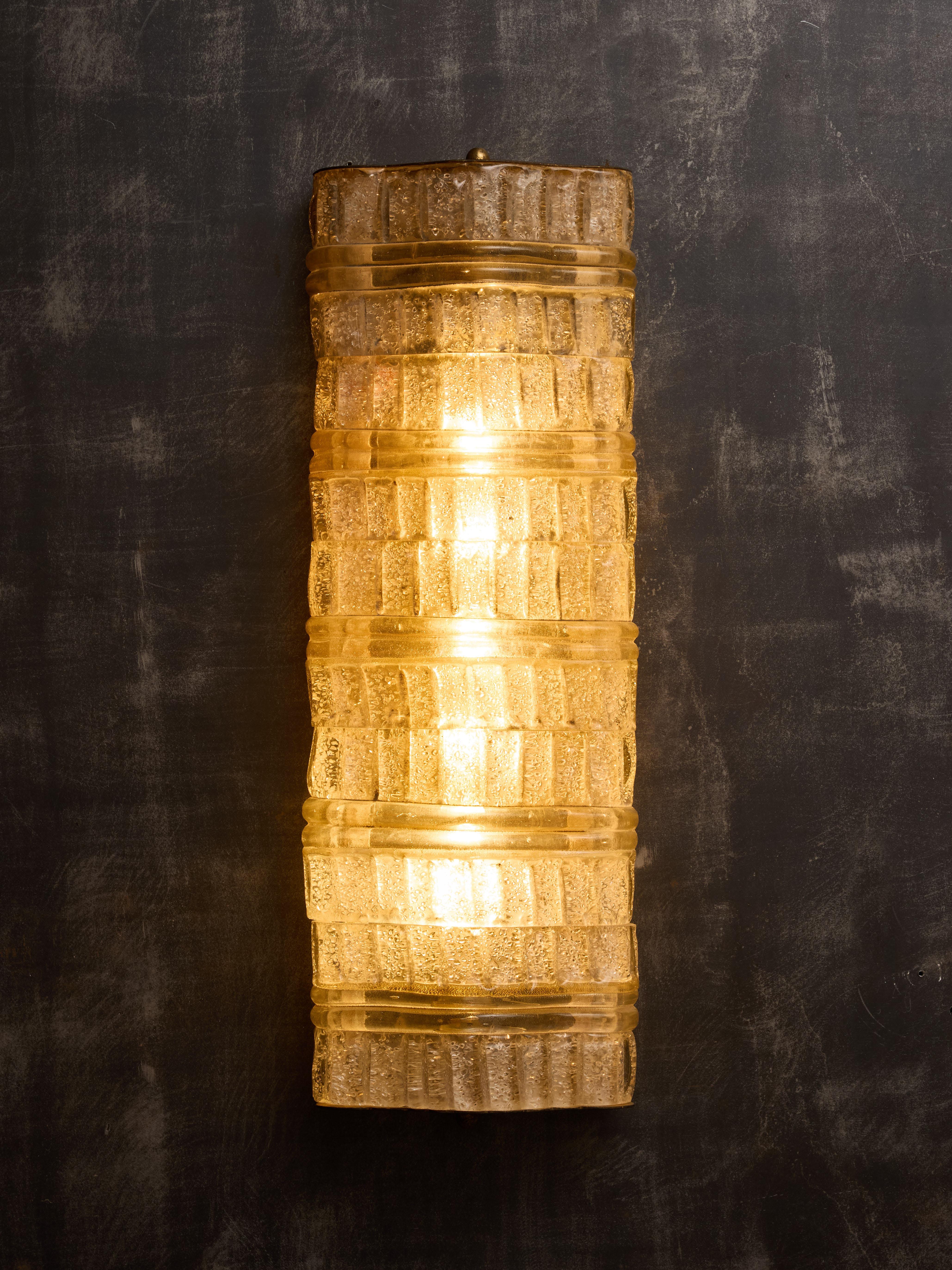 Discover this exceptional collection of ten wall sconces designed by Ercole Barovier in the 1960s. Each piece features a metal frame, brass accents, and stunning Murano glass. The design includes five elegantly curved Murano glass elements stacked