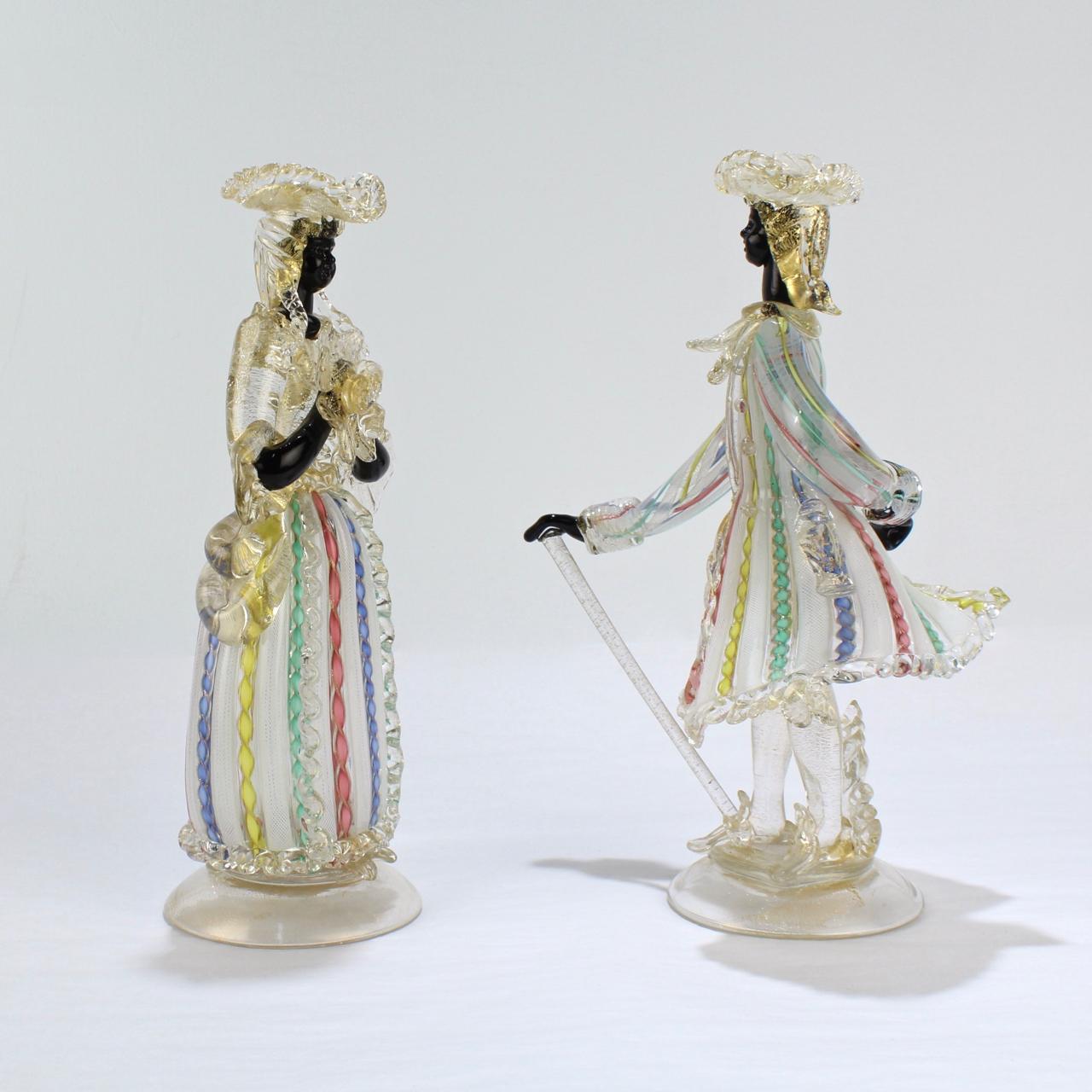 A rare pair of vintage Venetian glass figurines.

Comprised of a Gentleman with tricorn hat and cane in a zanfirico frock and a Lady with tricorn hat and flower bouquet in a complementary dress.

Each on a round base with gold inclusions.

Height of