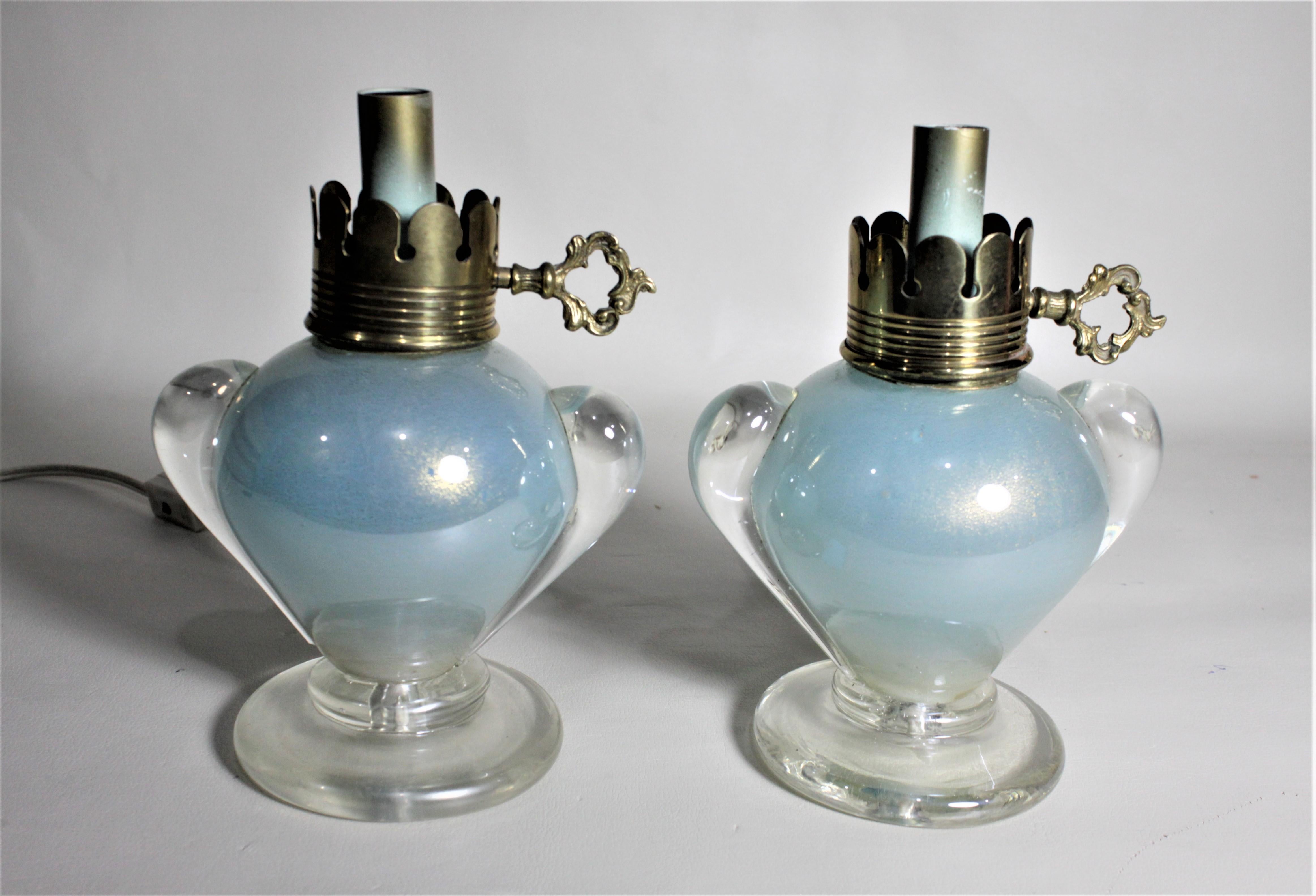 This pair of small lantern styled art glass table lamps are unsigned, but are presumed to have been made in Italy and designed by Angelo Seguso in circa 1970. The two lamps are done in a thick clear art glass with aqua blue inclusions with swirled