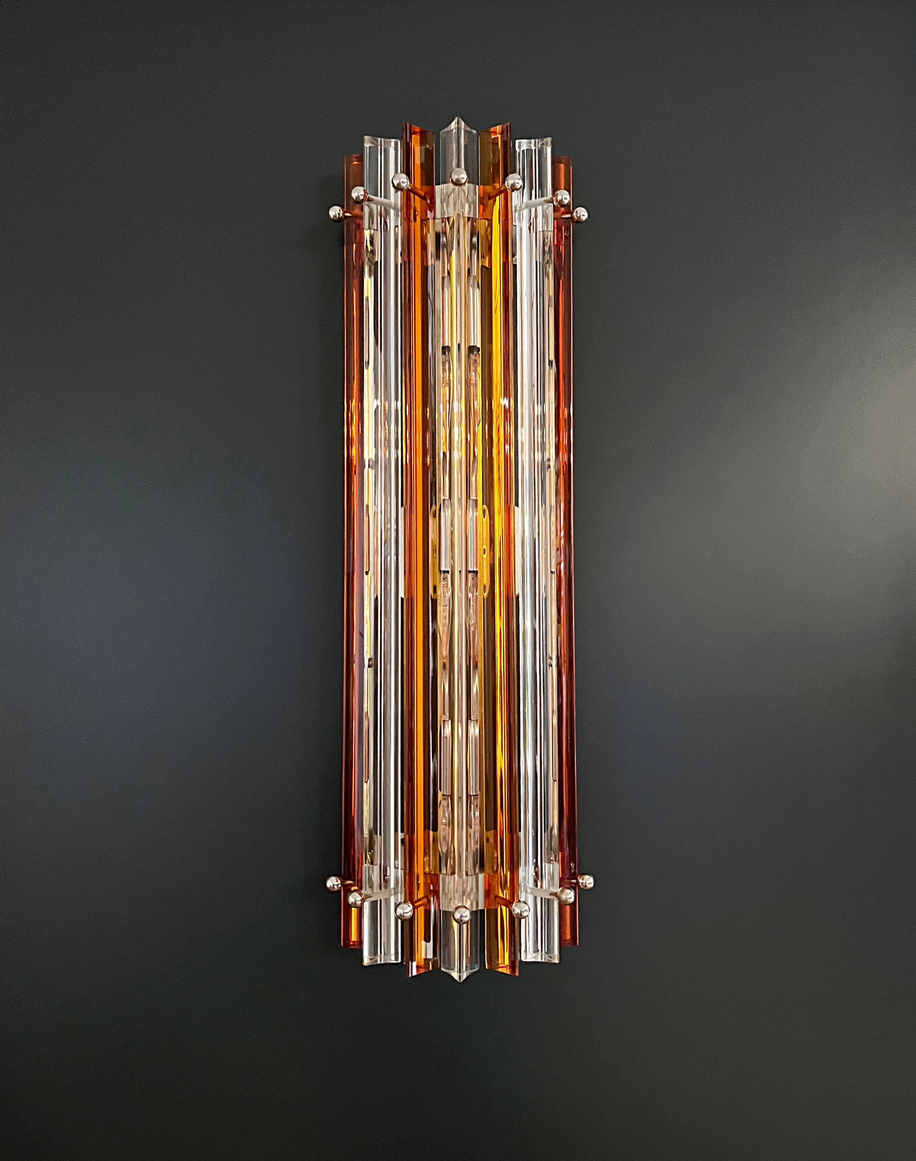 Fantástico par de apliques de Murano vintage realizados con 7 prismas de cristal de Murano (triedri) para cada aplique en un marco de metal cromado. La forma de este aplique es de columna. Los vasos son transparentes y de color ámbar. Los apliques