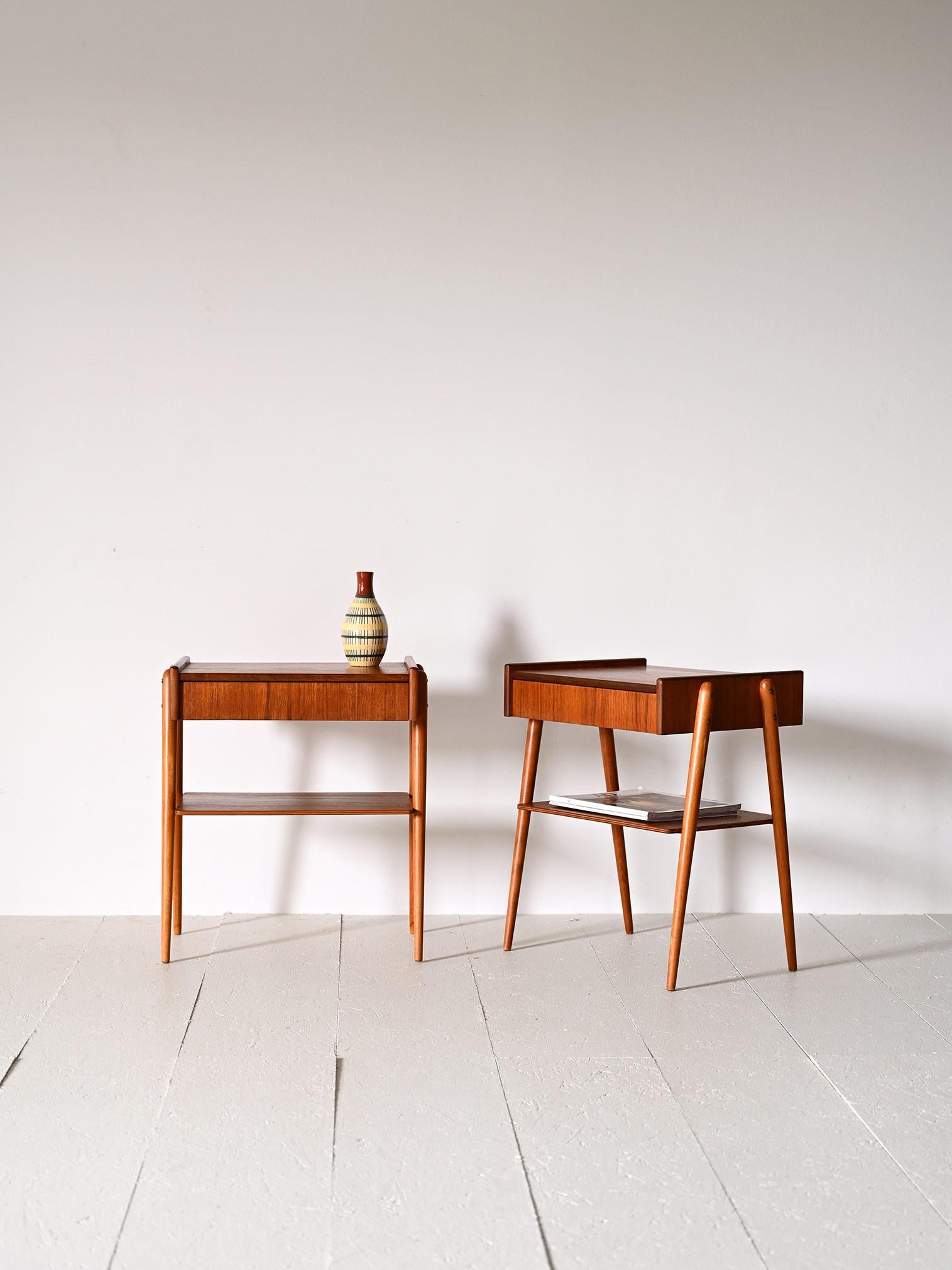 Original vintage Scandinavian teak bedside tables.

This iconic model was produced by the Swedish company AB Carlström & Co Möbelfabrikn in the 1950s. 
The linear teak wood frame is enhanced by the concealed drawer and long tapered oak legs. A
