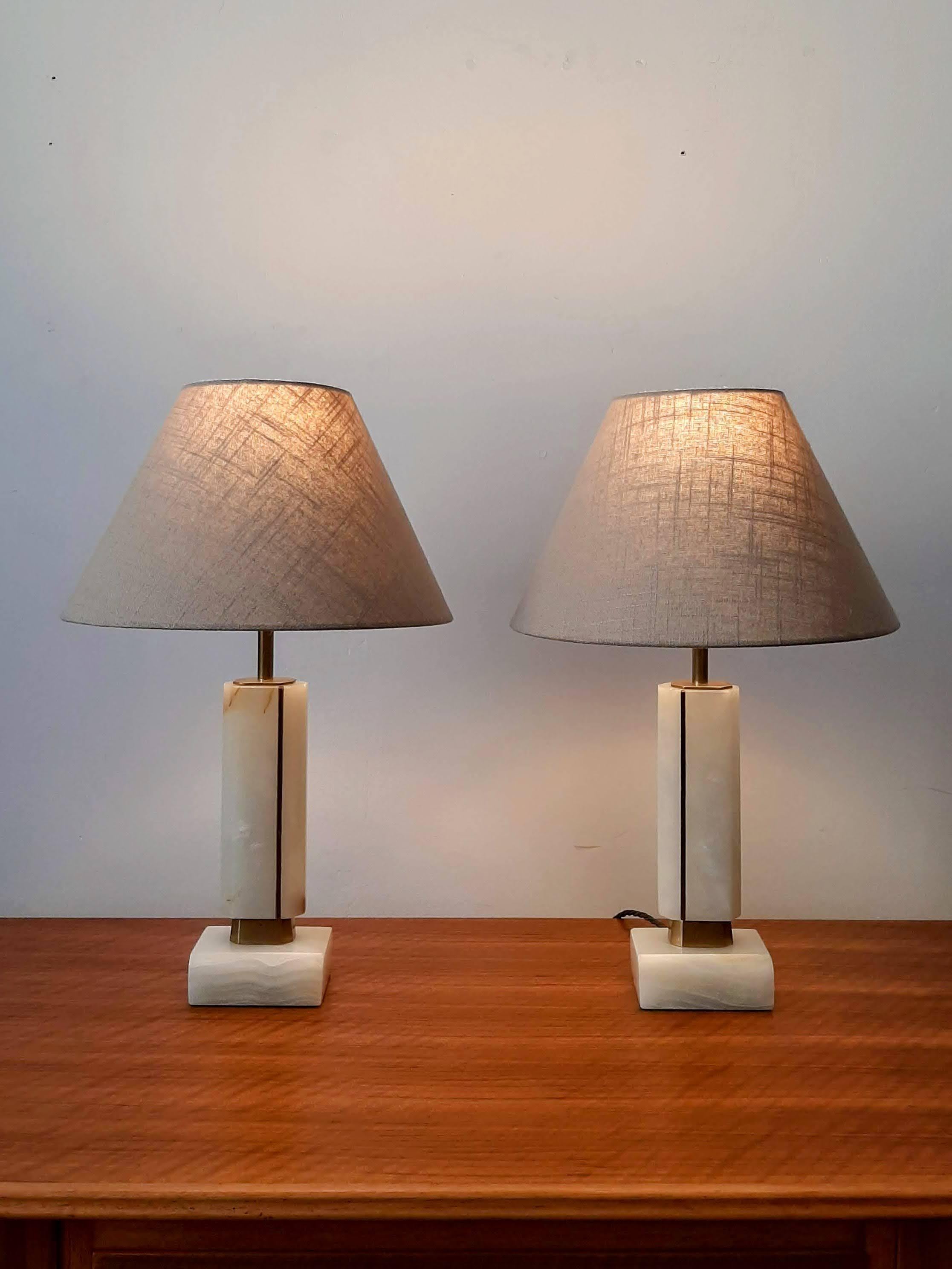 Élégante paire de lampes de table en onyx avec détails en laiton datant du milieu du 20e siècle. Les lampes sont en excellent état et ont été recâblées avec du câble en tissu vert torsadé et des douilles en laiton. Les nouvelles teintes de tissu