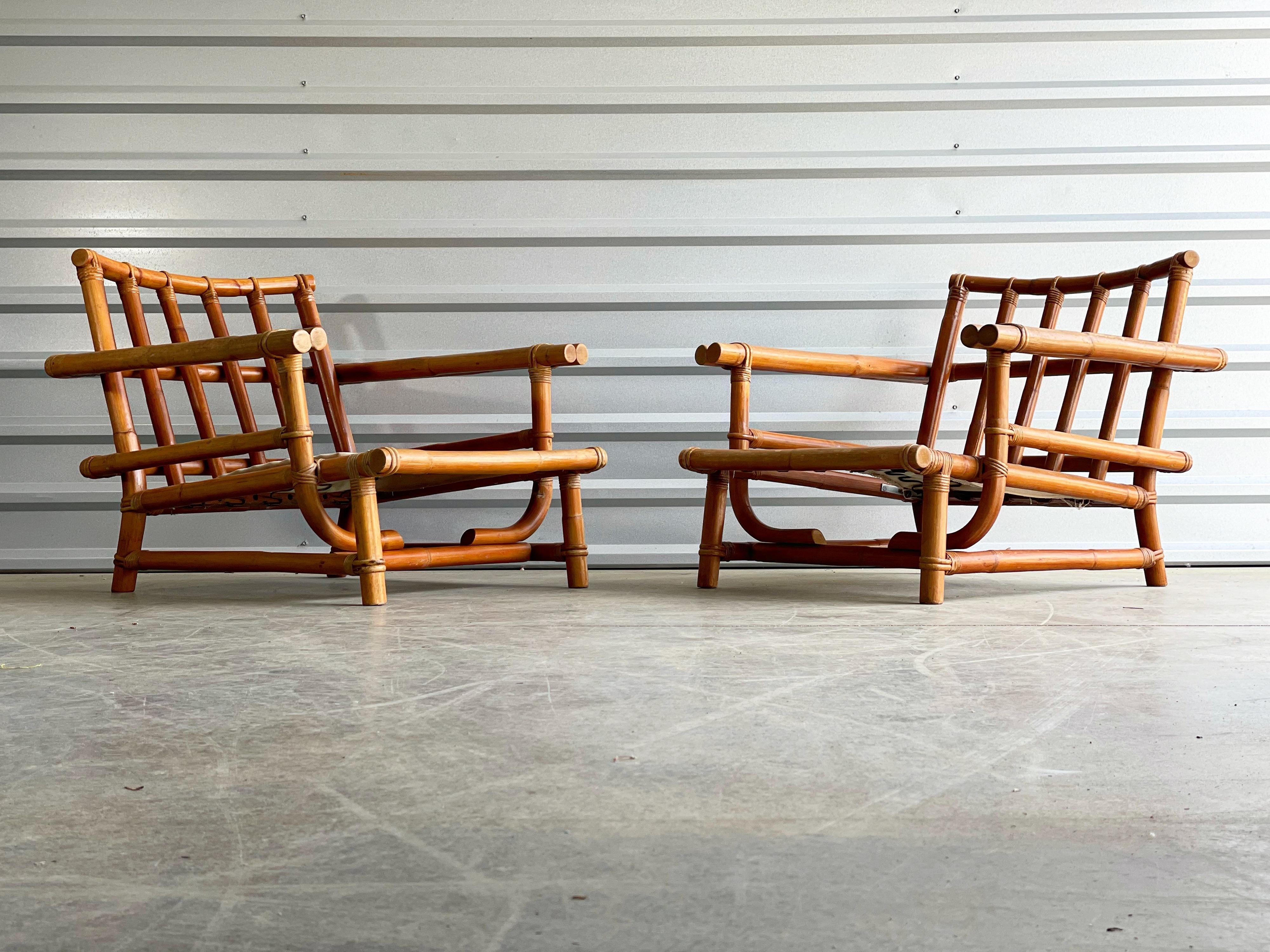 Pair of substantial low slung bamboo rattan lounge chairs by Ficks Reed. Built, circa 1960. Exquisite craftsmanship and top notch materials. Set includes two lounge chairs and one matching ottoman. Rattan frames are in excellent condition with a
