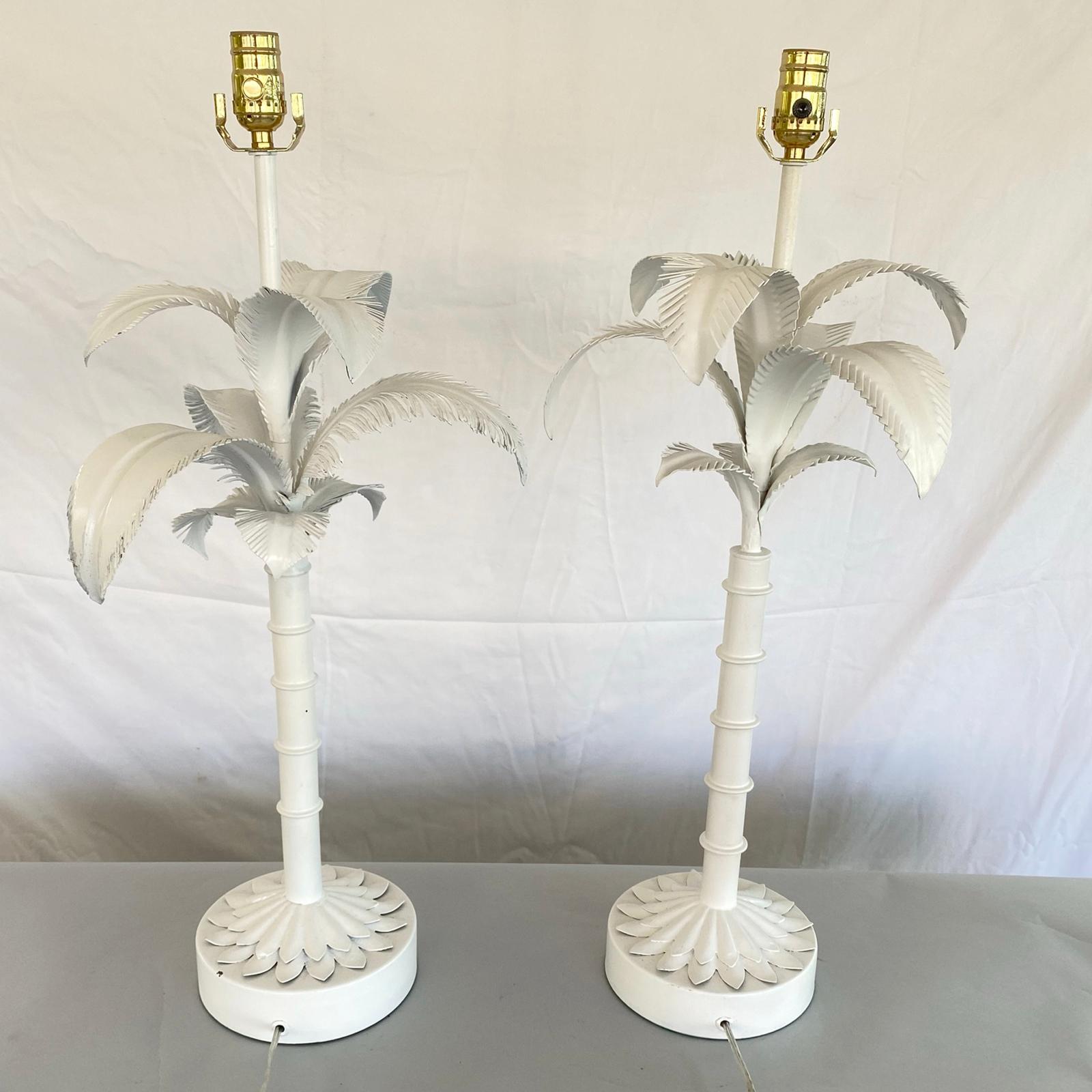 Pair of classic vintage painted tole palm tree lamps, each segmented tree trunk surmounted by fronds, on round plinth base with a graduated foliate decoration on its foot. 

Stock ID: D2988.