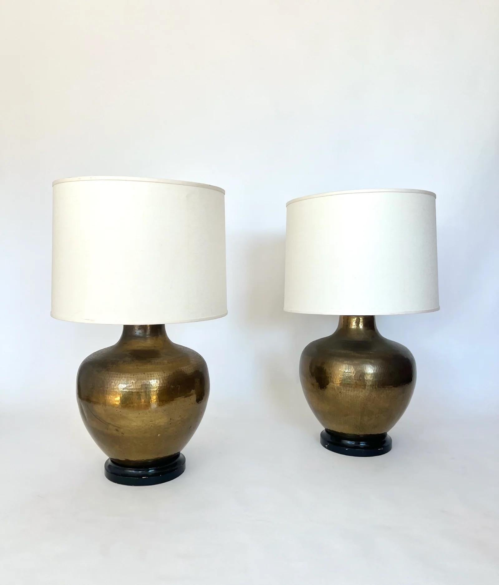 Cette étonnante paire de lampes de table vintage de Paul Hanson, datant des années 1960-1970, présente des corps généreux en laiton martelé à la main avec une patine chaude et vieillie, posés sur des bases en bois ébonisé.  Paul Hanson a été actif