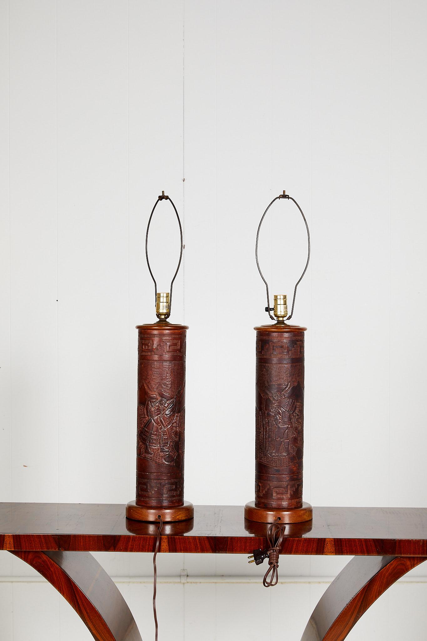 Mid-20th century Peruvian friendly pair of leather cylinder shaped lamps with original hand tooled and embossed leather scenes of landscapes with llamas framed by a Greek key border. The Spanish Colonial style lamps are mounted onto turned wooden