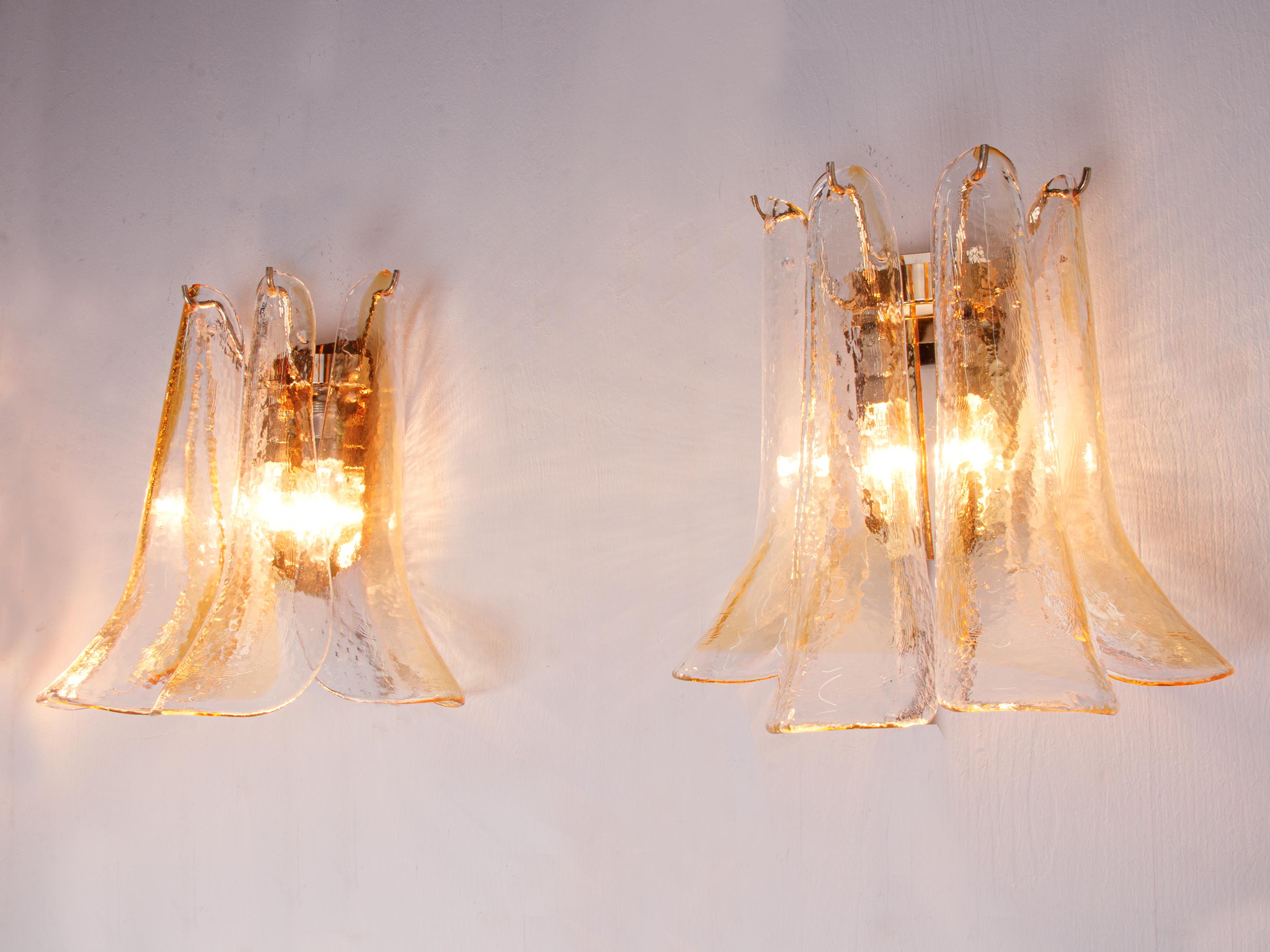 Elegant pair of vintage wall sconces with clear and amber tinted hand blown Murano glass petals on a golden frame.
Each lamp petal is unique and partially marked with an 