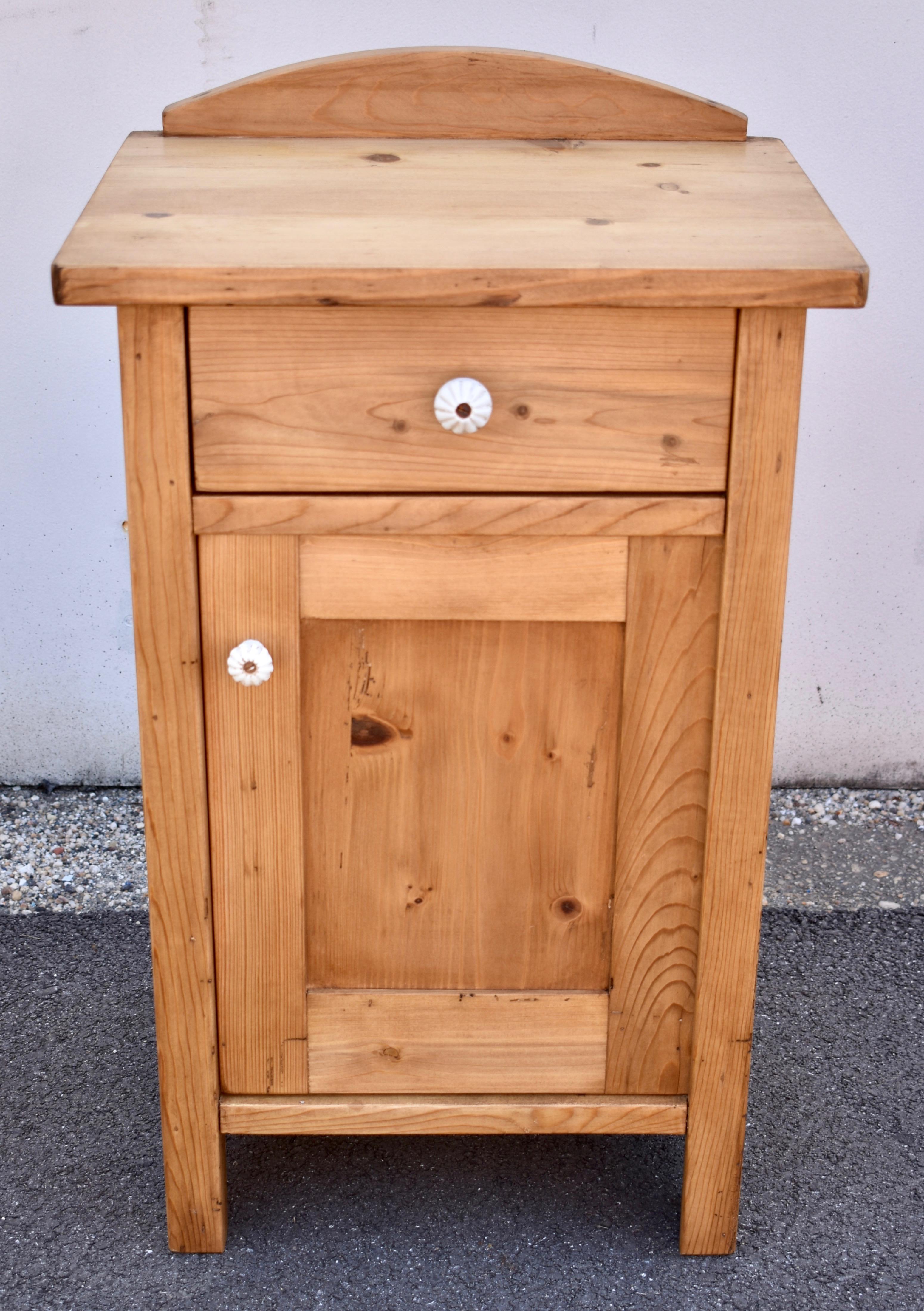 This is a particularly nice pair of pine nightstands, sturdy and “stocky” with clean straight lines and built of thick and heavy yellow pine.  The top is surmounted by a 3” high arched splashback, and the drawers are hand-made.  The plain side forms