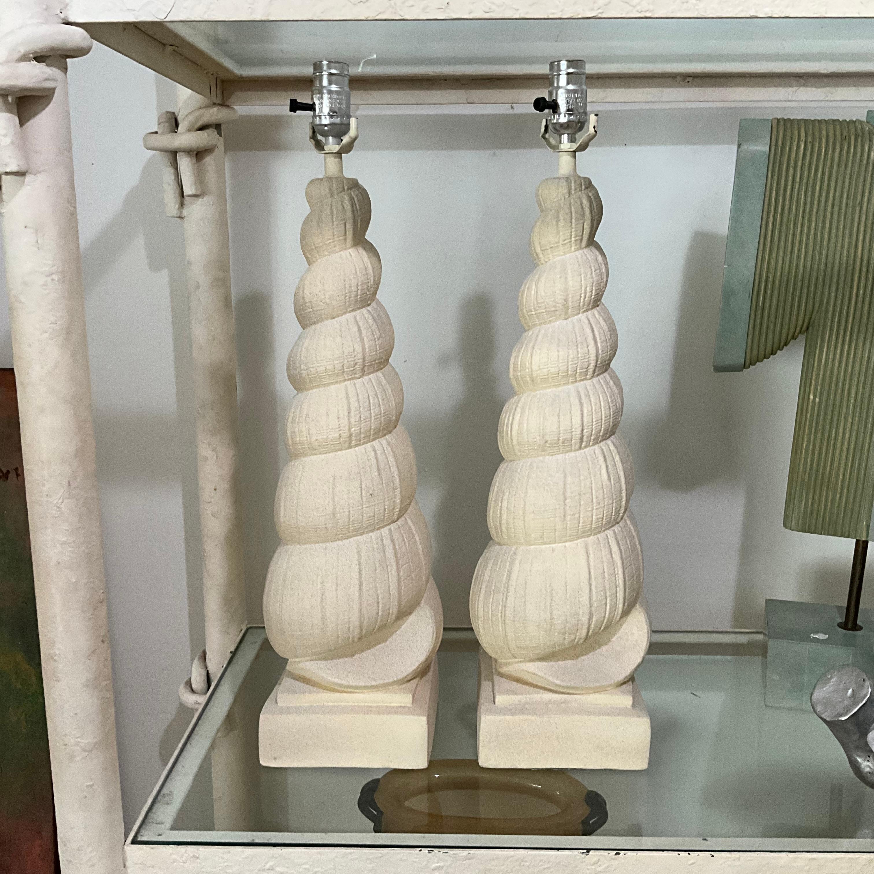 Sculpturale et côtière-chic, cette paire de lampes à coquillages en plâtre des années 1970 capture l'essence du design Organic Modern. Leur forme de coquille spiralée surdimensionnée et leur finition texturée en font à la fois des luminaires