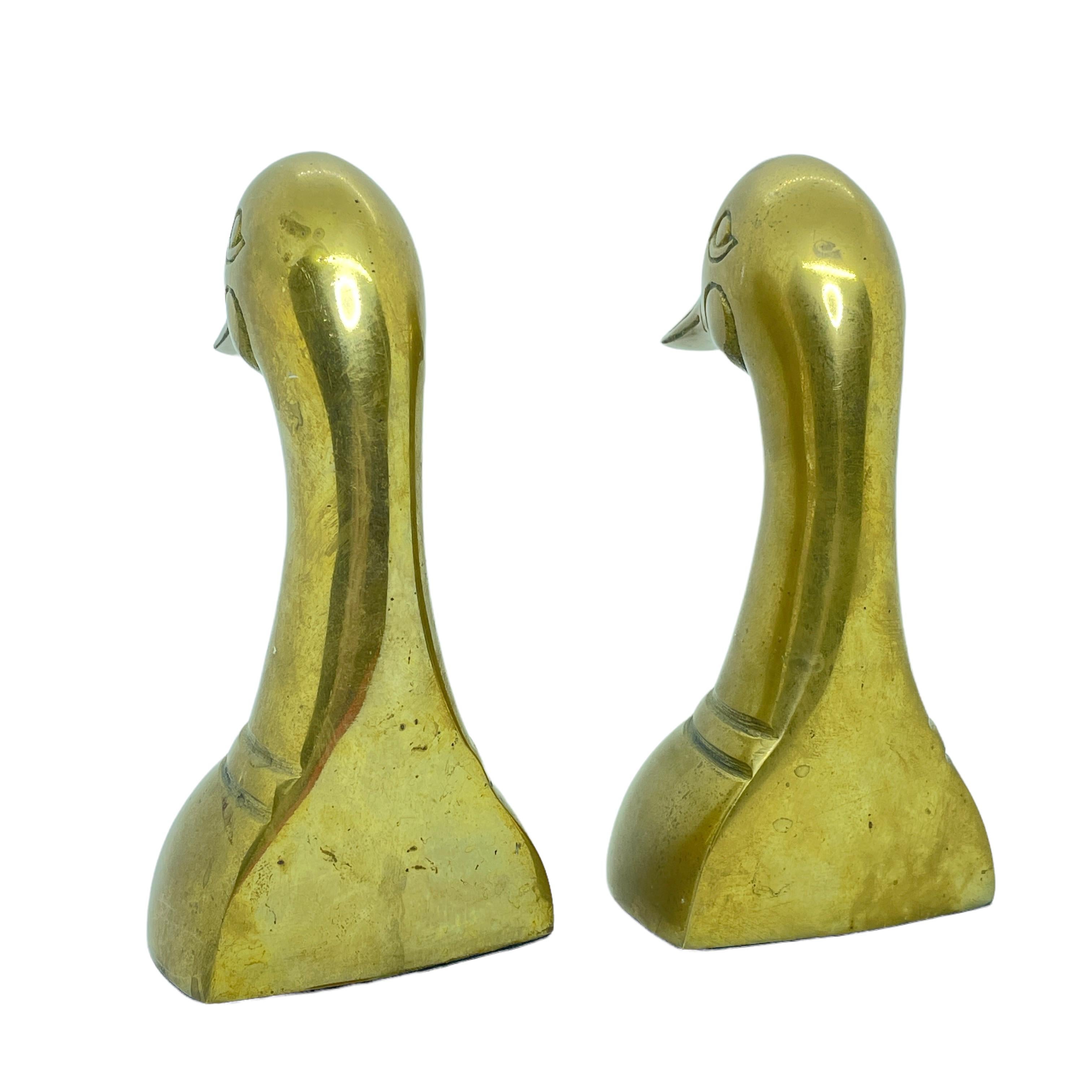 Vintage pair of polished cast brass duck bookends, circa 1950. Pair of polished decorative brass duck bookends in Sarried style. Very sturdy and heavy. Great for holding up books on a bookshelf or as paper weights on a desk or decorative animal