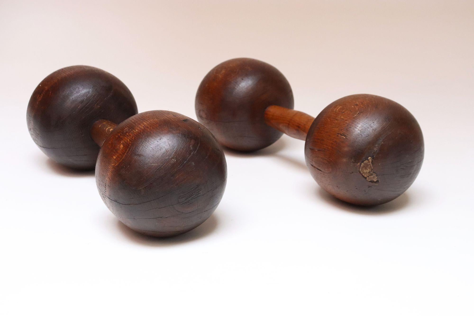 Haltères sculptés à la main, chacun provenant d'une seule pièce de bois continue accentuée par des lignes sculptées (vers les années 1930, États-Unis).
Bois de teinte naturelle, parfaitement vieilli avec une riche patine/salissure/fentes d'âge et