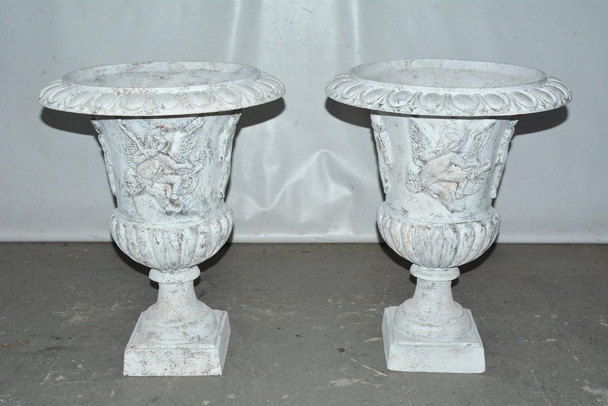French cast iron putti angel decorated neoclassical style urns taken from the classical Grecian form. 2 sets available.  Garden urn or planters can be used to decorate indoor or outdoor adding style and interest to any space. Great aged patina.