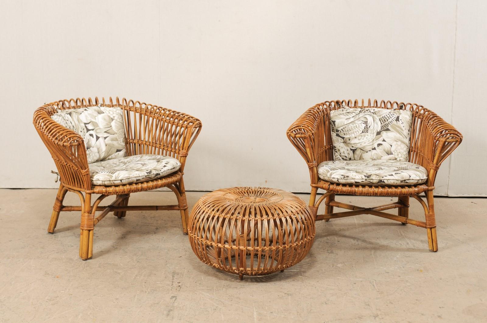 This vintage American patio set includes a pair of rattan chairs, with seat and back cushions, and single matching ottoman. This rattan seating arrangement was designed with casual comfort in mind. The two chairs feature bent rattan wrapped backs