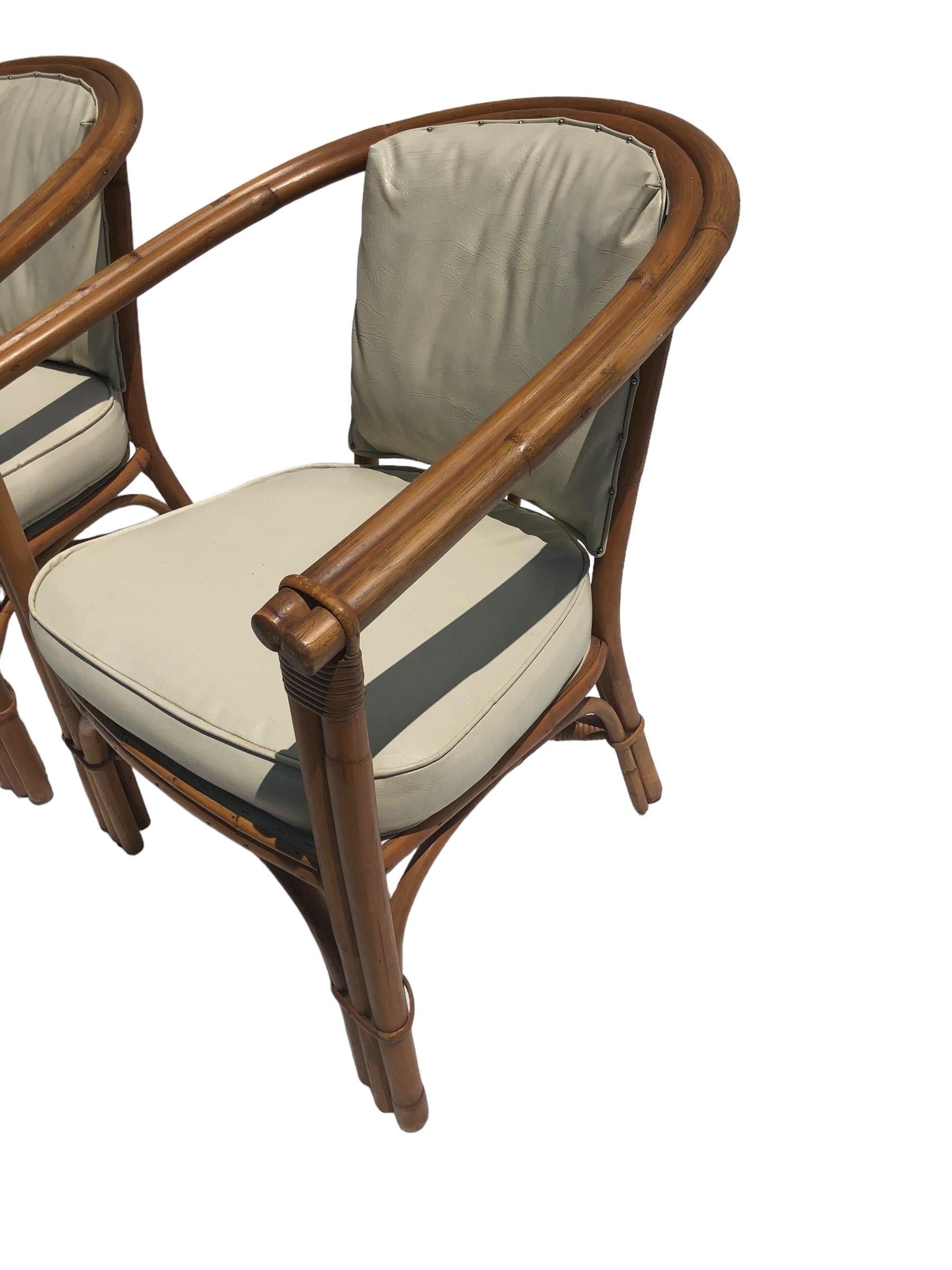 Paire de chaises vintage en rotin avec assise en vinyle.  Robuste grâce à la construction du dos en fer à cheval.

Veuillez nous contacter pour obtenir des devis d'expédition compétitifs.