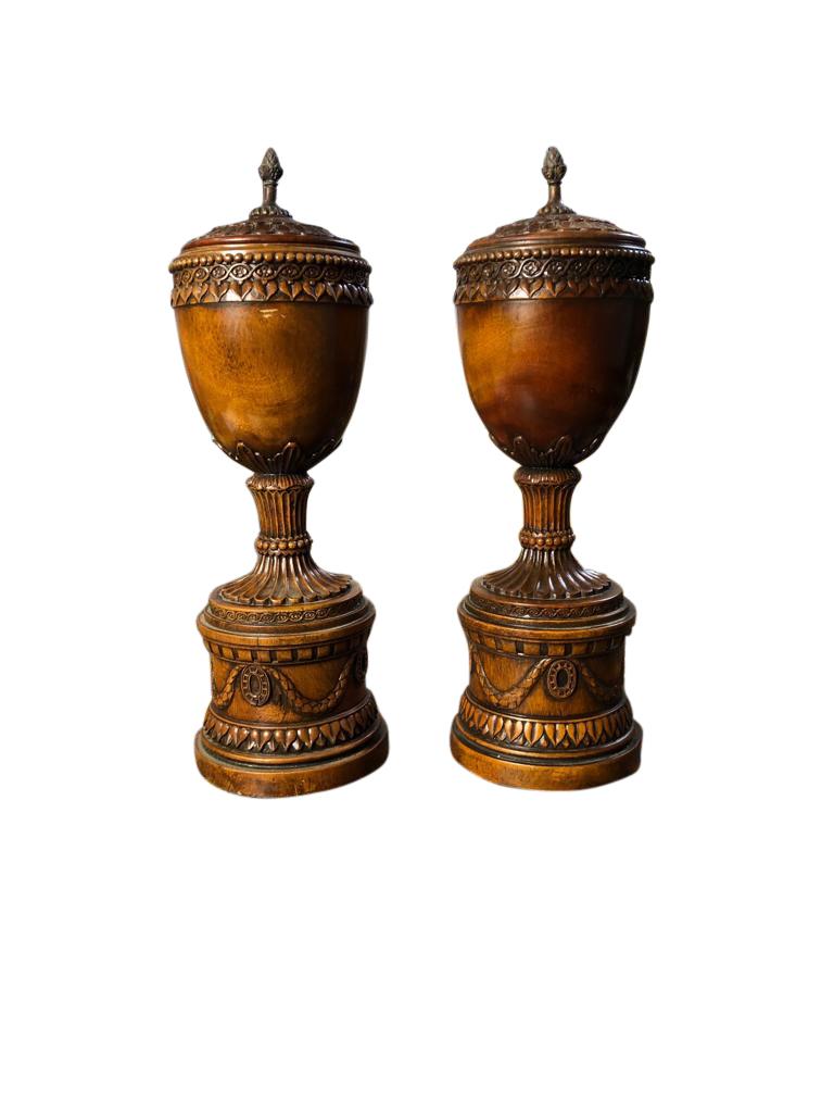 A stylish pair of cherrywood mounted, Regency style, lidded wooden pedestal urns, Italian, 20th century. This amazing pair have a superb patina finish, and are offered in great condition. Perfect for home decoration and storage. Ready for home use