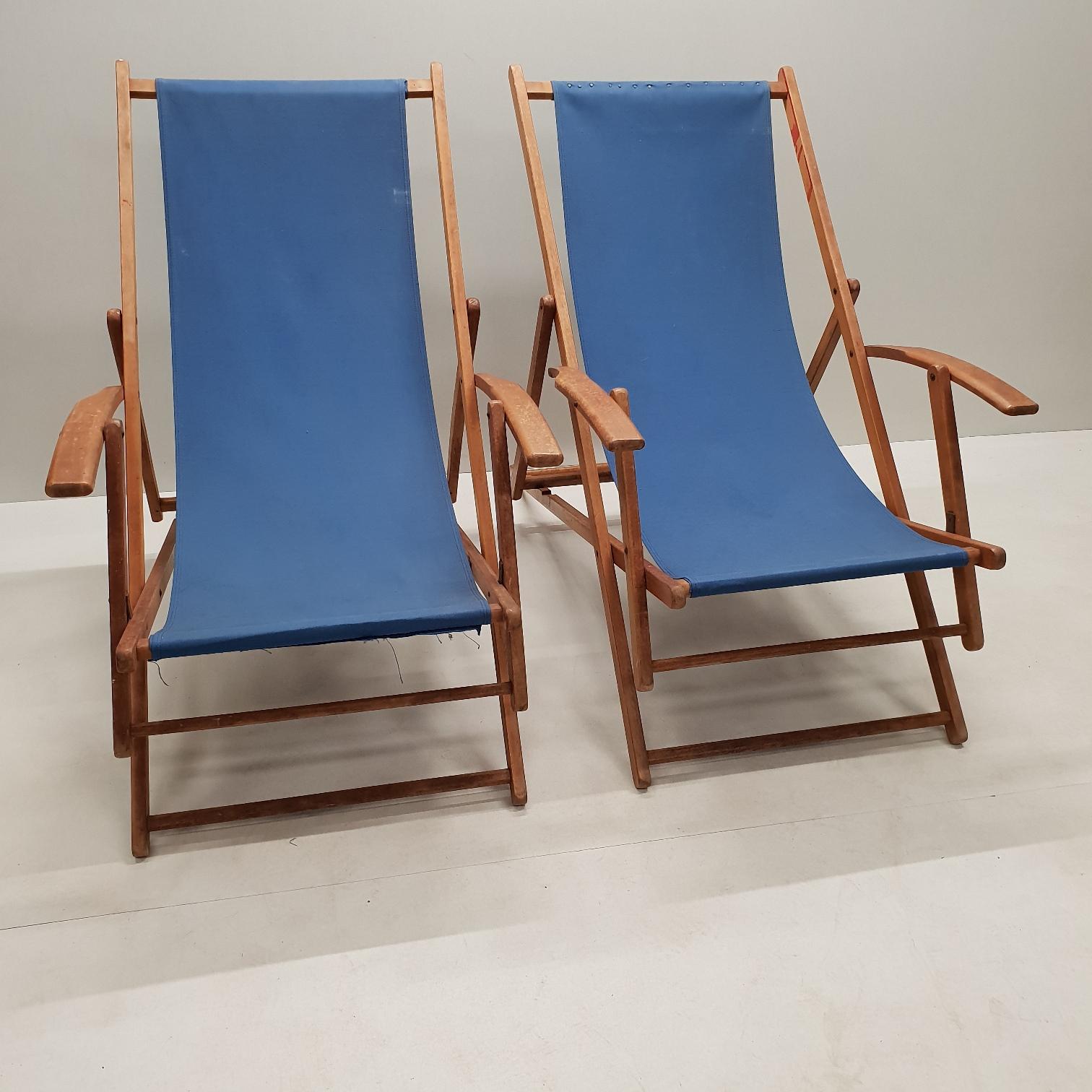 Pair of wooden adjustable folding beach chairs with armrests, 1950s.
The canvas upholstery is not original and not professional upholstered.
Beautiful details and wooden frame.
Very nice chairs for next to the swimming pool.