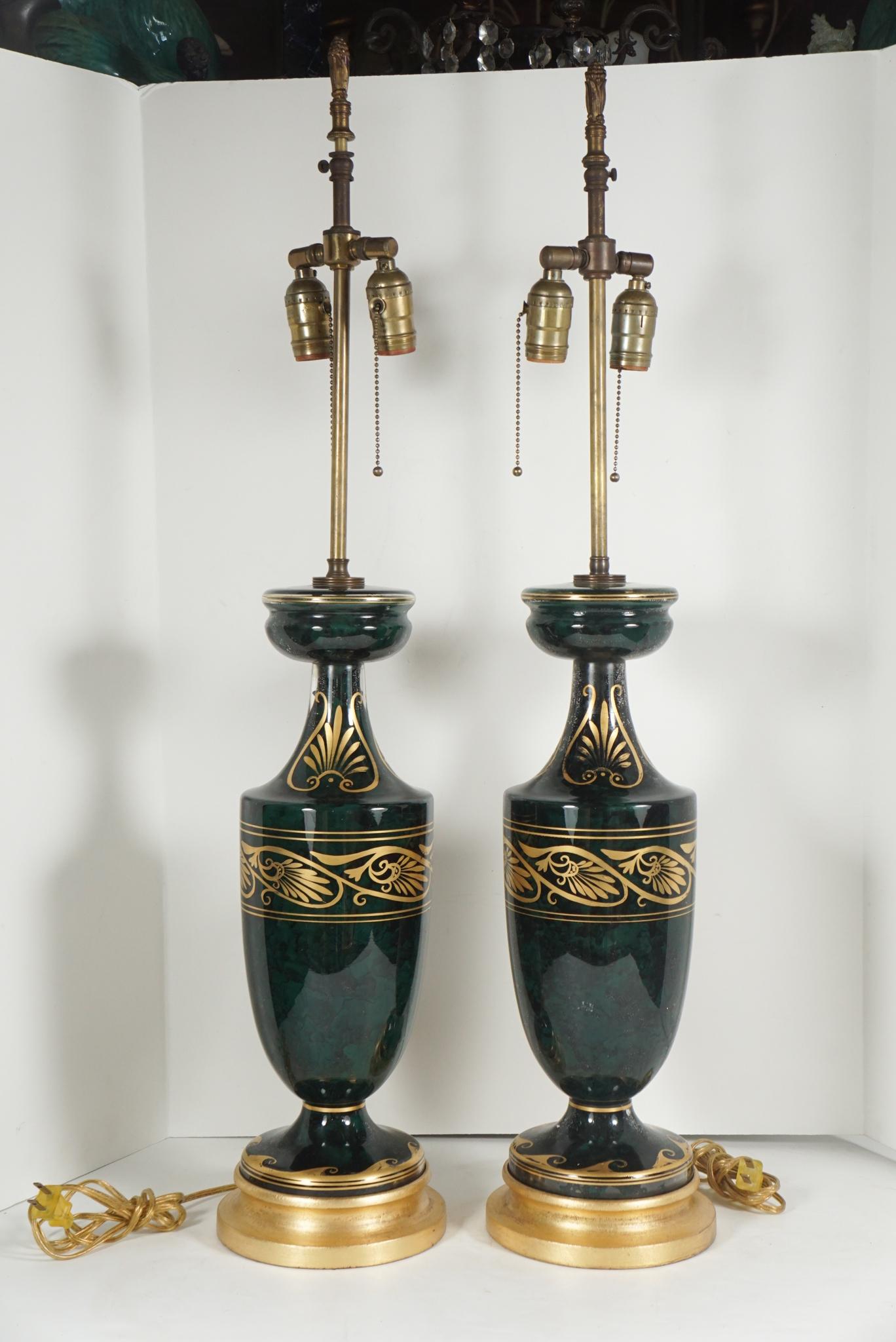 Made in America circa 1940 this pair of lamps is crafted by blowing the glass vases and then reverse painting them on the inside. These are done in a rich marbled green / black that has been further set off by the addition of outside gilt stenciling