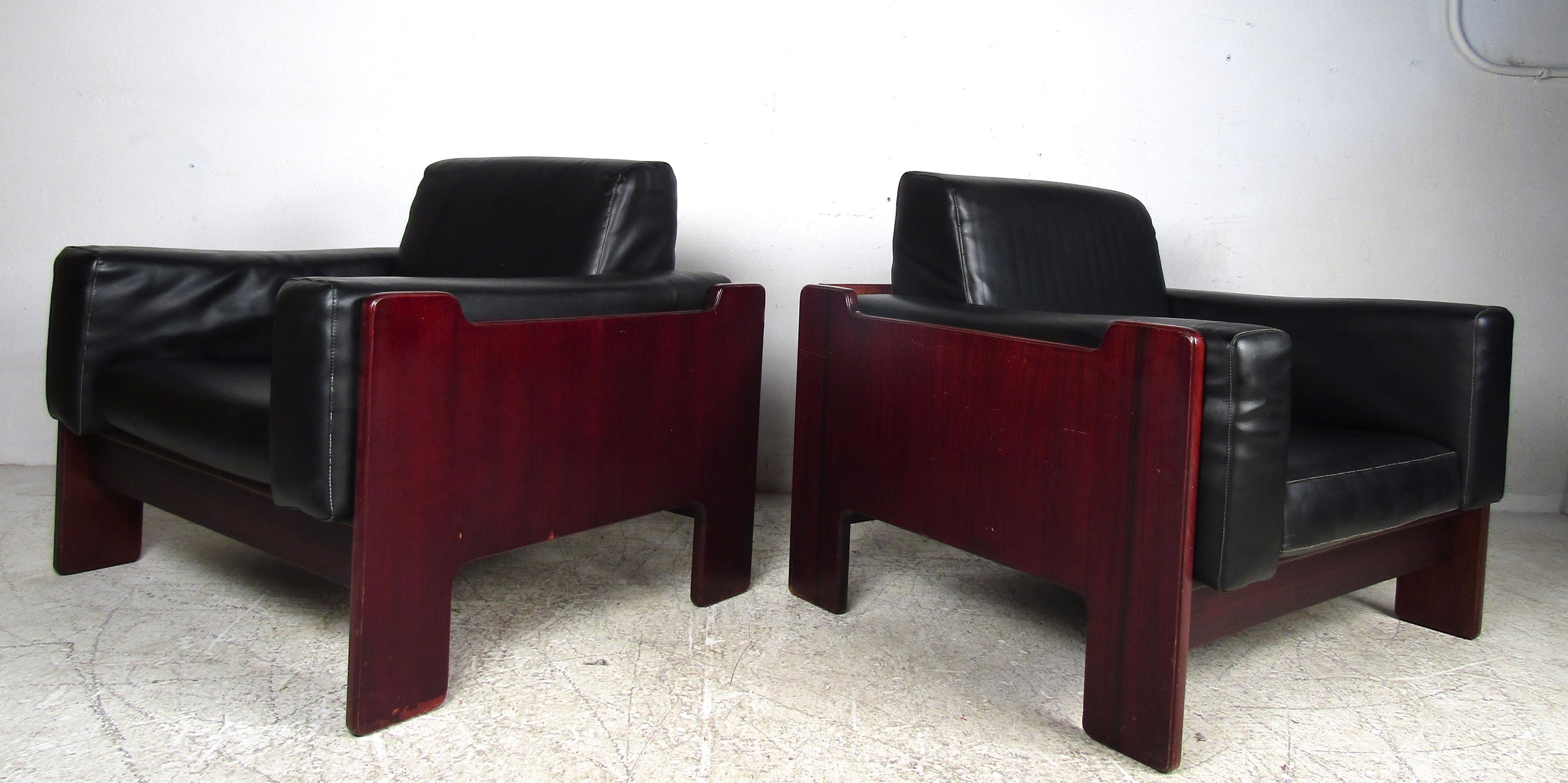Dieses atemberaubende Paar Mid-Century Modern Lounge Chairs hat eine bequeme Würfelform mit übergepolsterten, abnehmbaren Kissen, die mit schwarzem Vinyl bezogen sind. Ein elegantes und robustes Design, das in jeder modernen Einrichtung einen