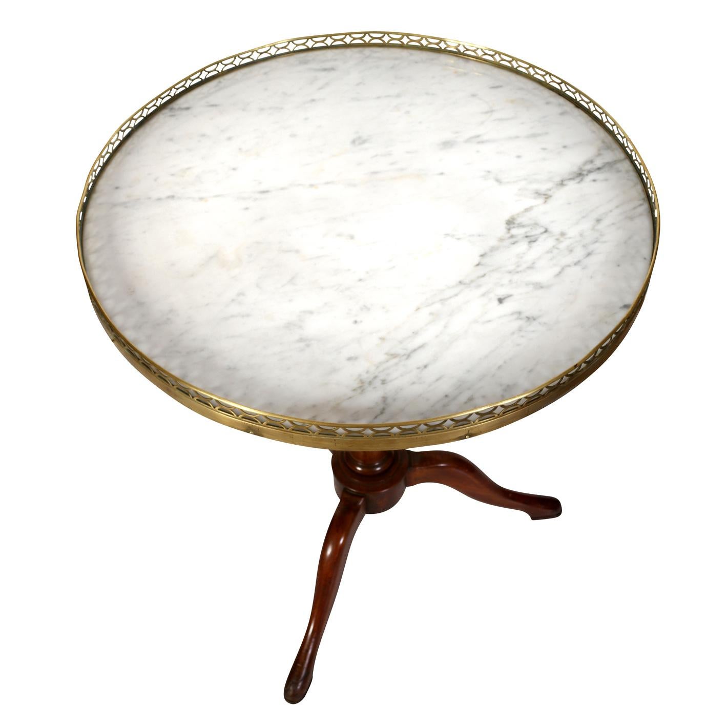 A pair of round marble top side tables with pierced brass gallery rail and a fluted wood pedestal base with curved tripod legs.
