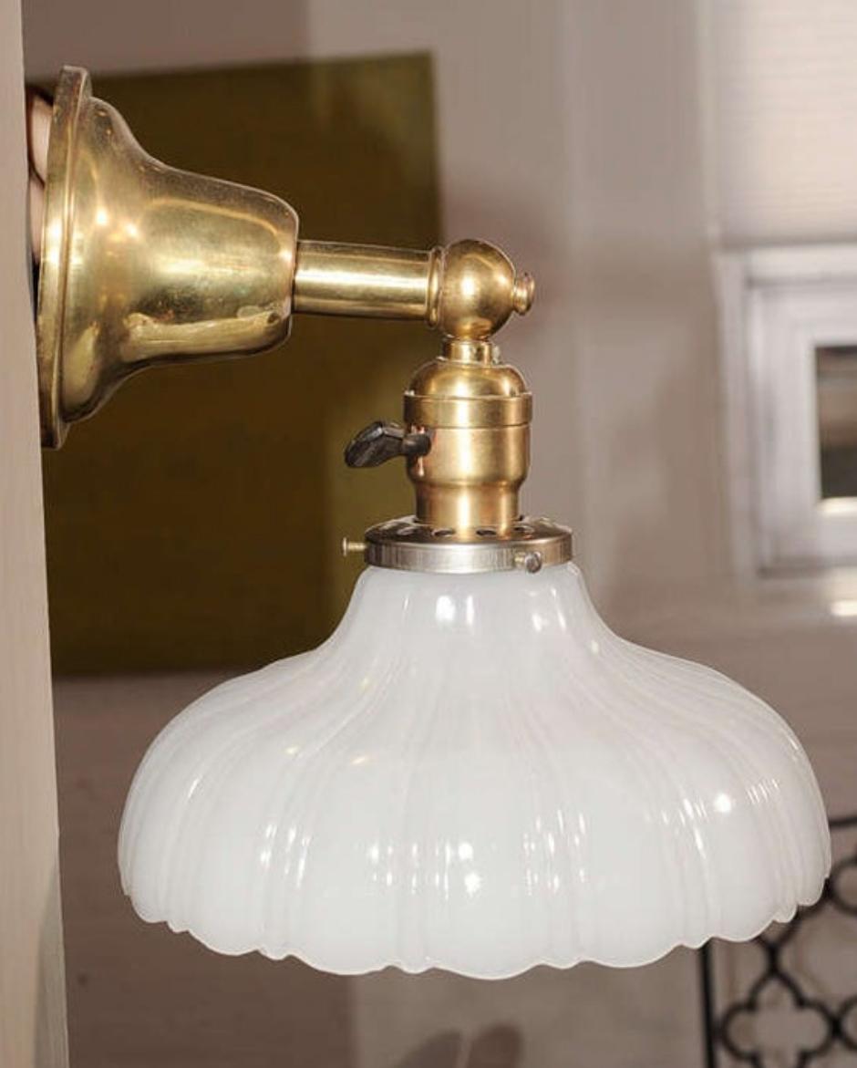 Pair of brass wall sconces or lamps with scalloped milk glass shades. USA, circa 1930.

Recently rewired with new sockets. Each sconce takes one standard base bulb (60 watts max).

Dimensions:
8.75 inch width overall (same as shade diameter)
8 inch