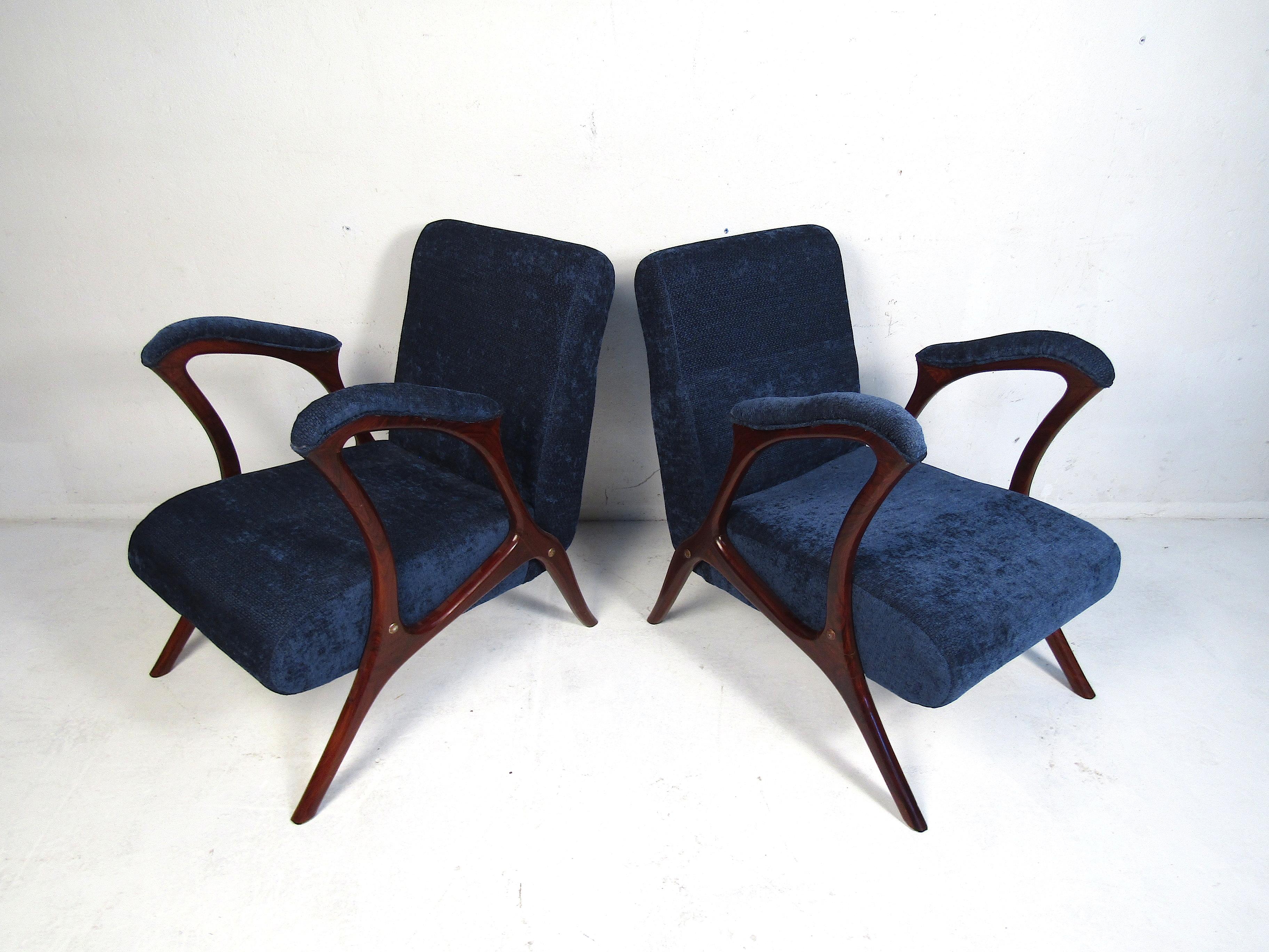 Very unusual pair of midcentury armchairs. Sculpted rosewood frames with high armrests (27 inches high) and dark blue upholstery. This pair would make an interesting addition to any modern interior. Please confirm item location (NJ or NY).
