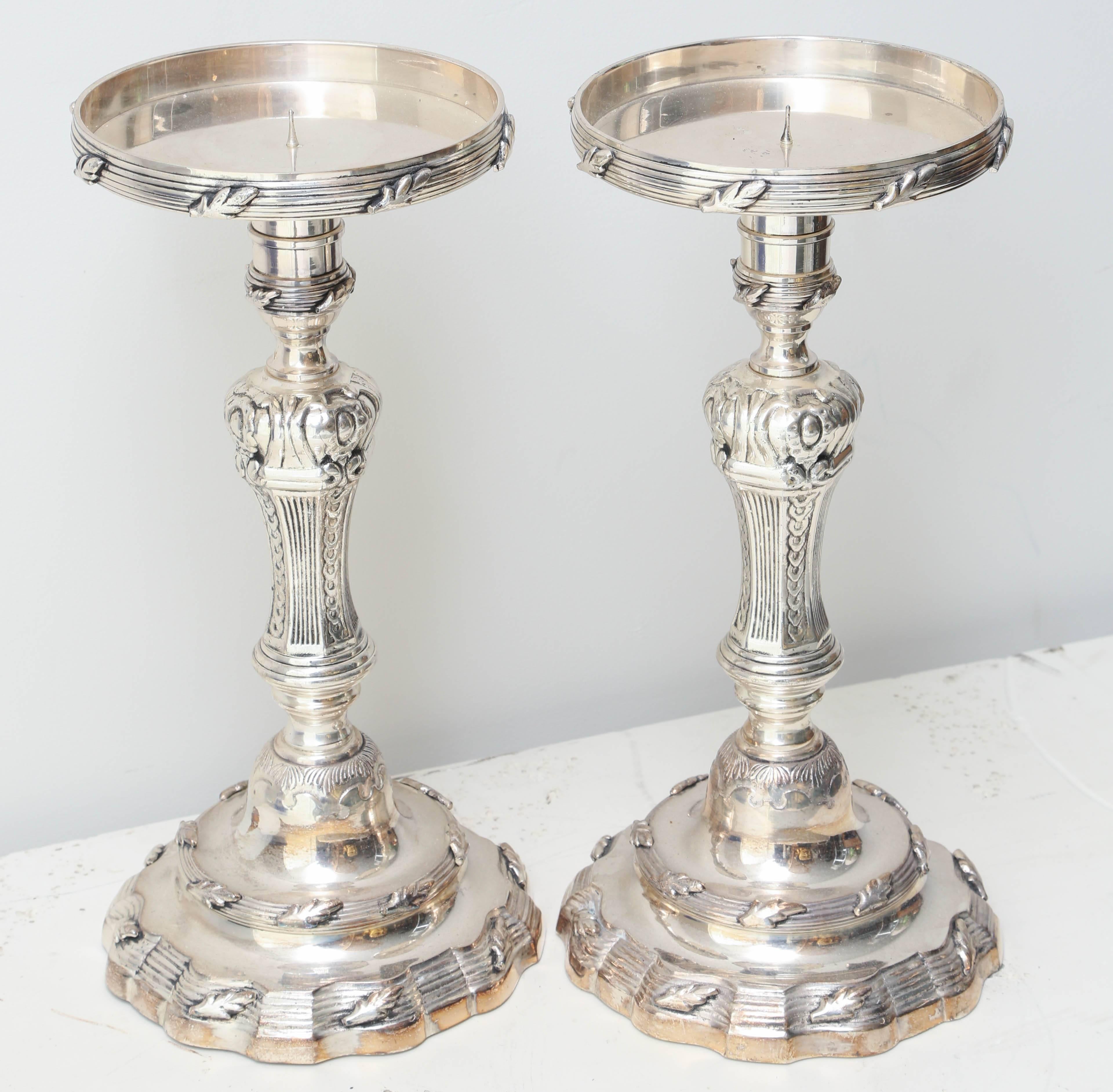 Silver plated pair of pillar candlesticks with intricate detailing.