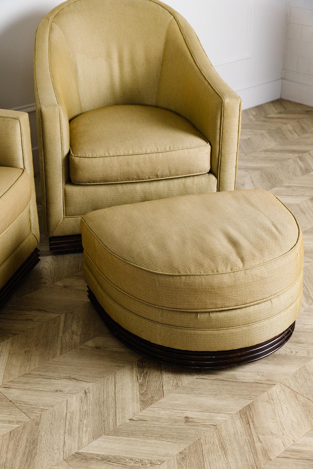 Pair of vintage swivel chairs with rattan bases and a muted gold upholstery. The pair comes with a single matching ottoman. The fabric is in amazing condition and does not need to be redone. The swivel mechanisms work great. These chairs are deep