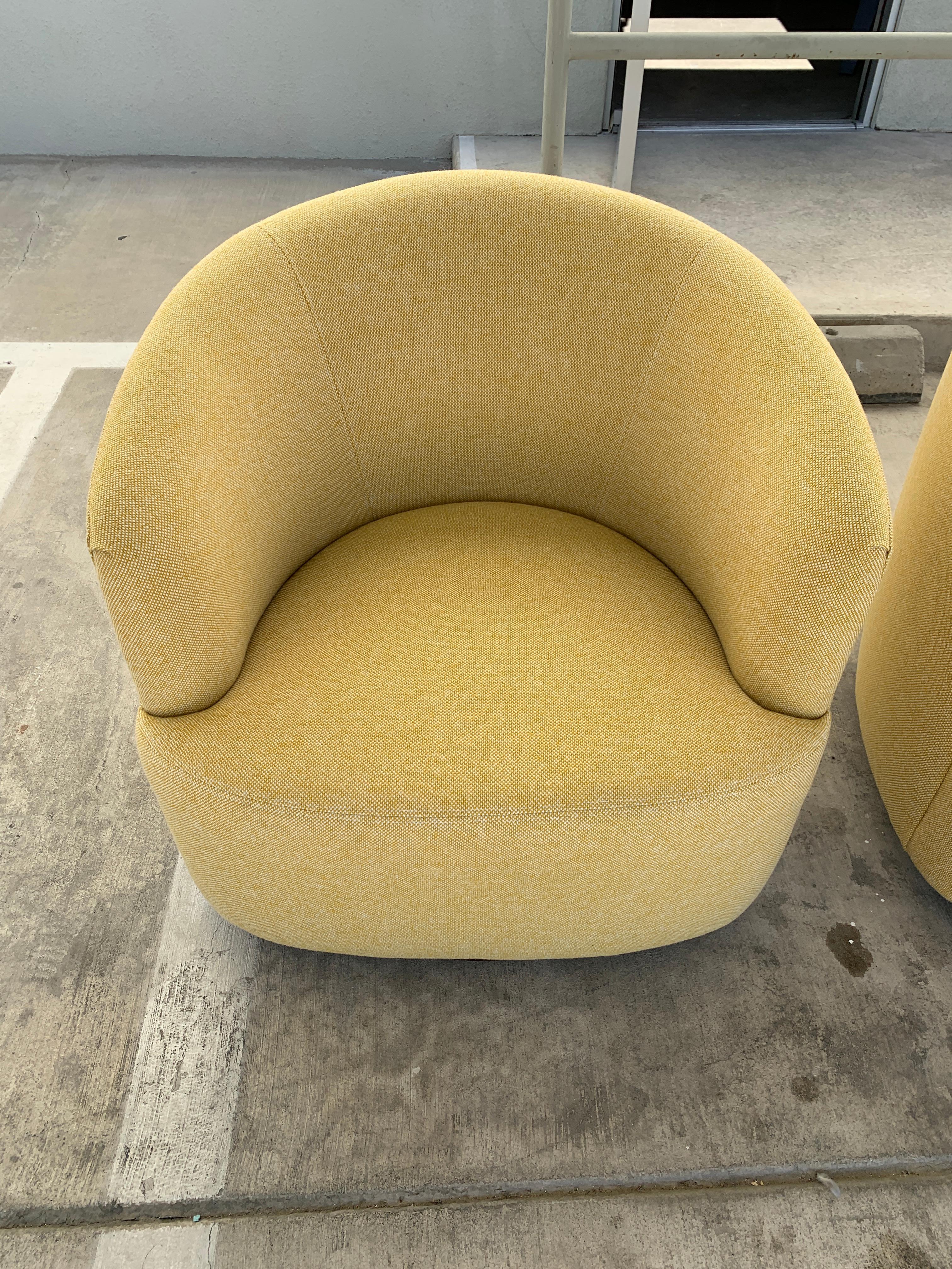 A pretty pair of vintage barrel chairs that swivel on wood circular bases. They have been completely redone and re-upholstered. The lines have been made cleaner and more modern. A beautiful and comfortable pair of chairs.