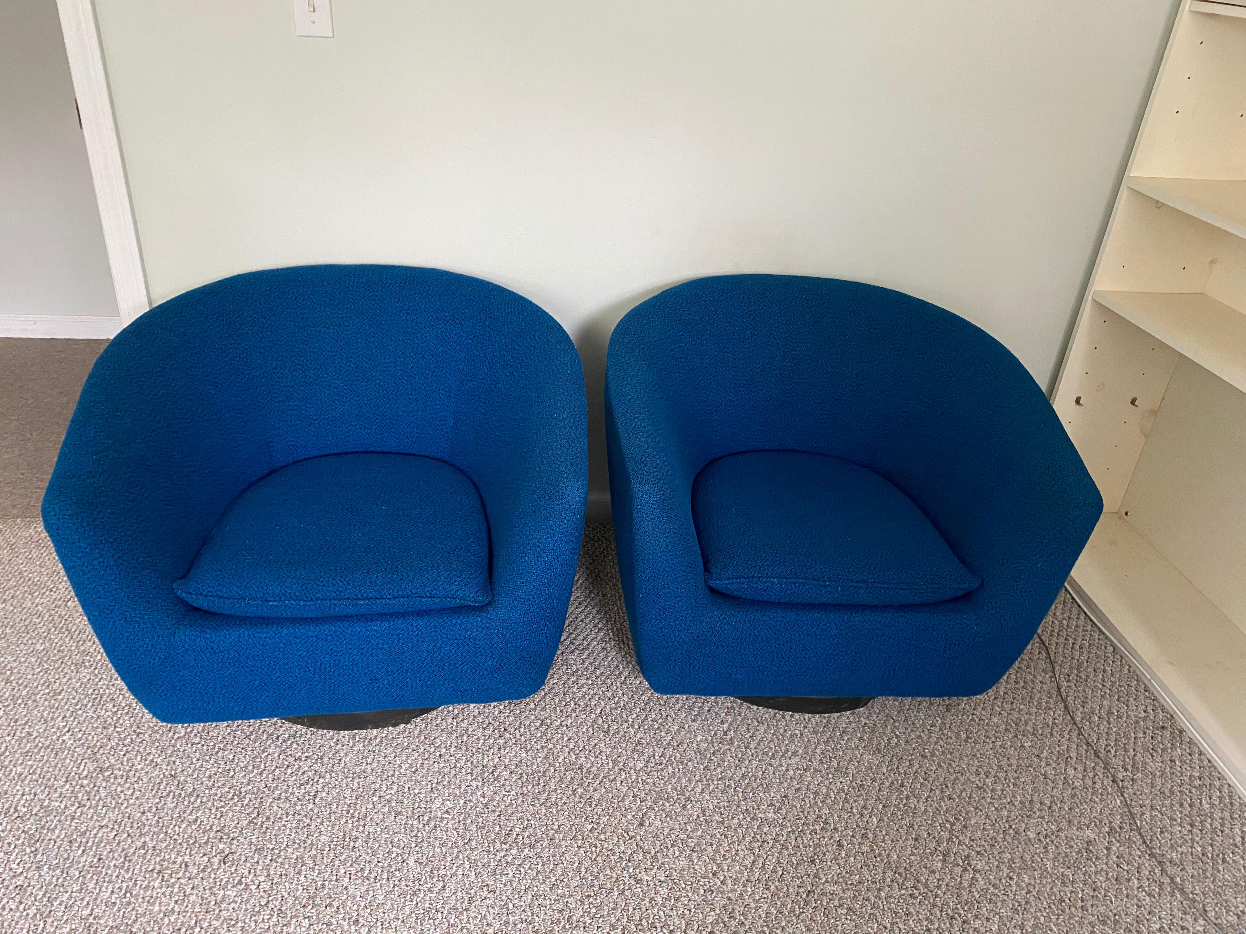 Elegant pair of unsigned vintage swivel lounge chairs, upholstered in the original blue wool. Wider shape than your typical barrel chair from this period. Veneer on base will be redone.  Price is for the pair.