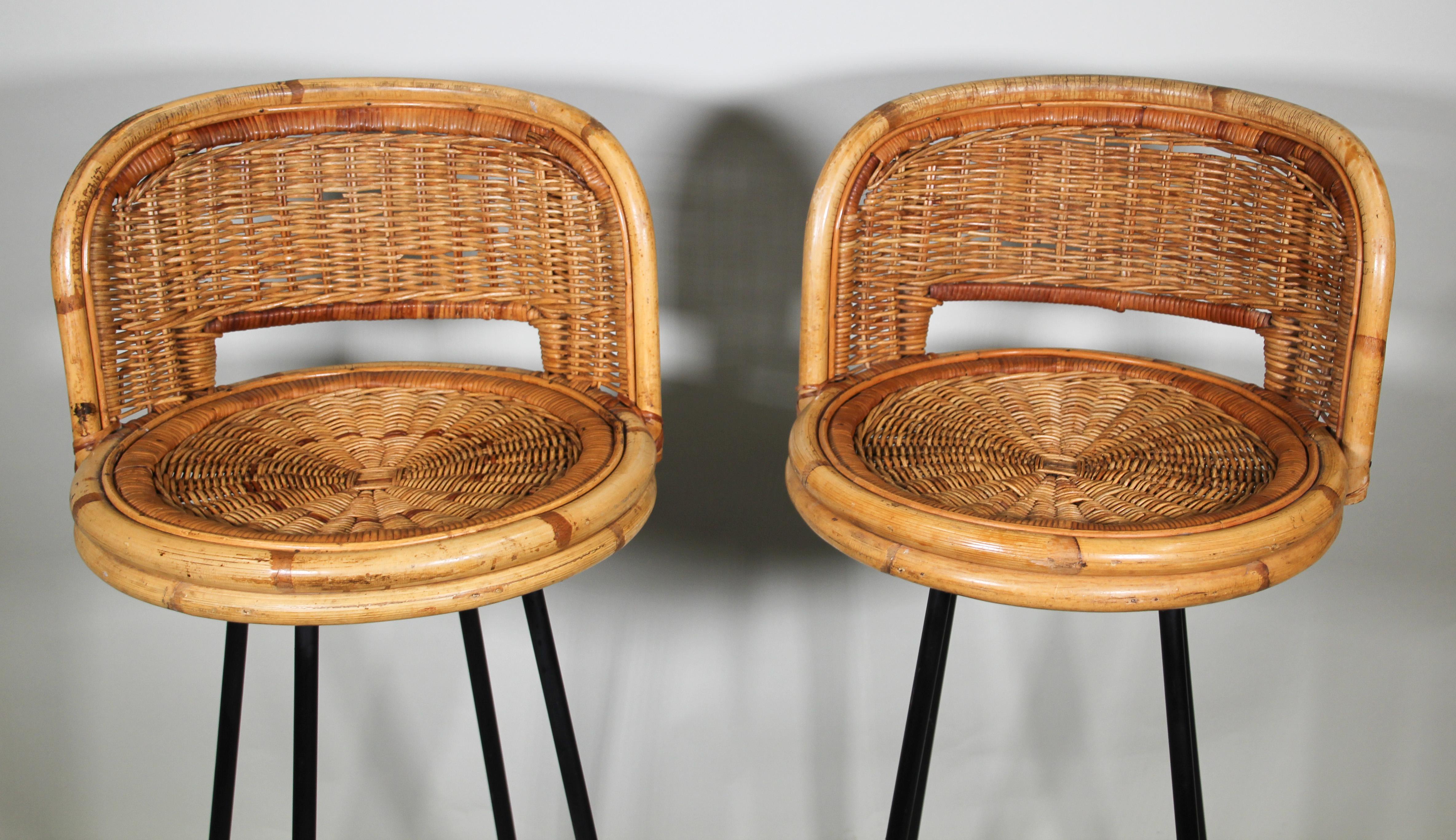 Vintage wrought iron swivel base rattan wicker bar stools in the style of Danny Ho Fong.
Black coated iron a frame built of 4 tall very thin round section splayed legs and a foot ring.
Woven rattan bucket chairs with black iron frame, swivel round