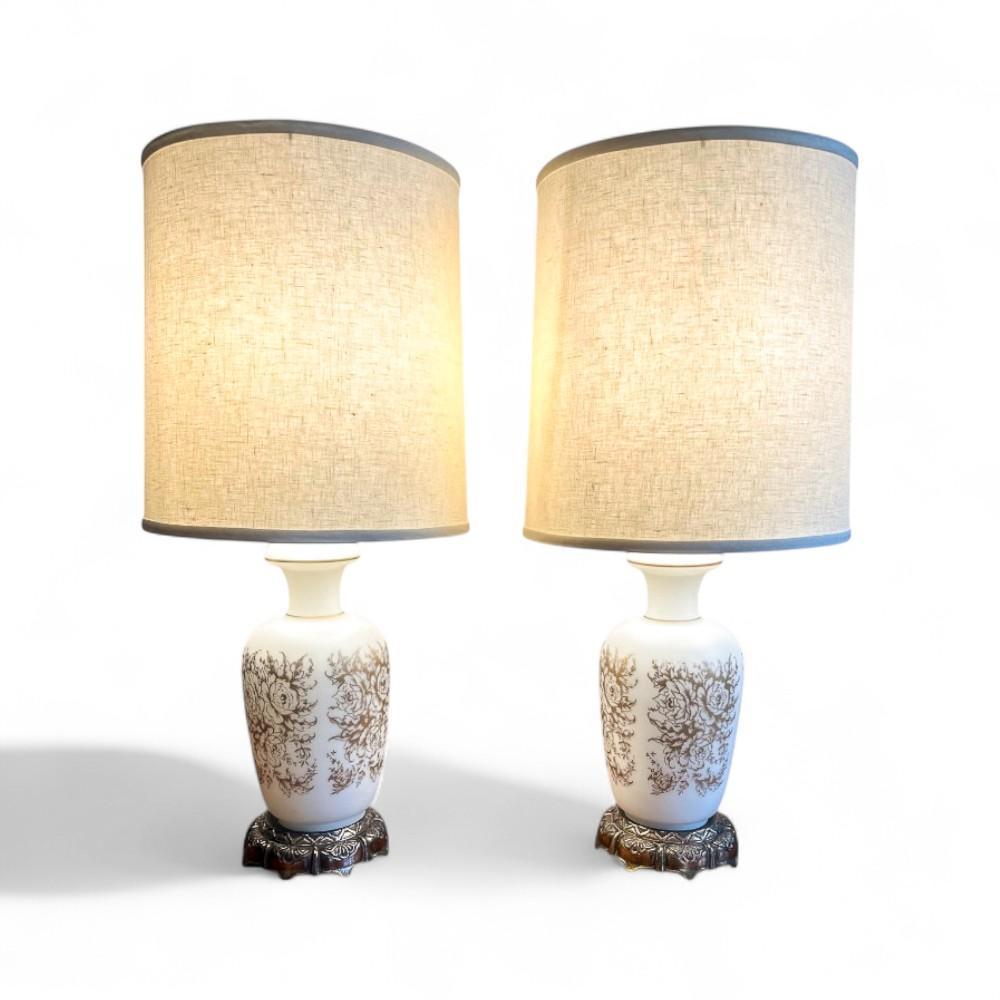 Pair of vintage white satin glass table lamps with integrated lights in the base and gold floral pattern. Can operate the top bulb and base light separately or together. In great condition with minimal wear to gold detailing and some patina on the