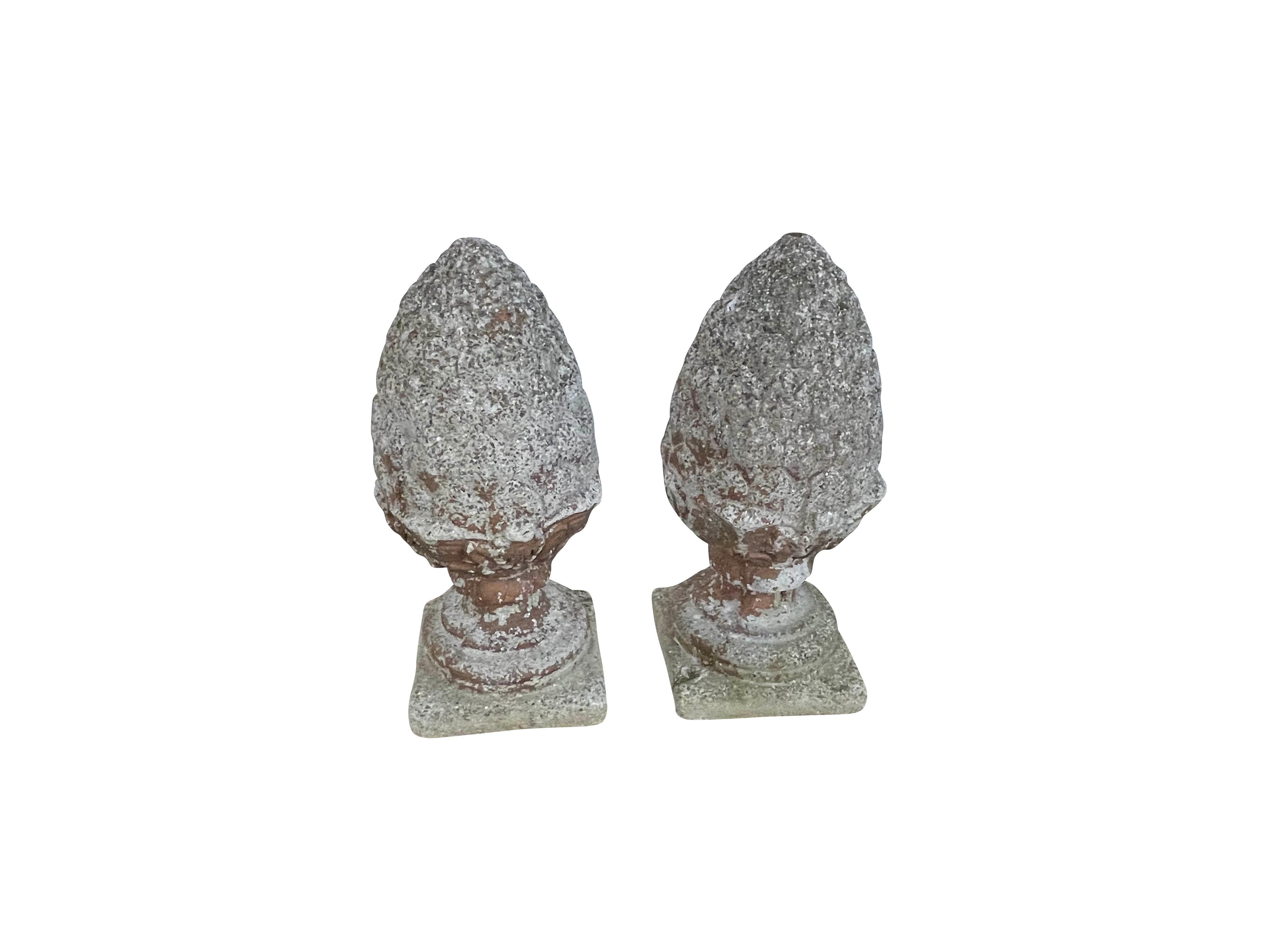 Dieses Paar Vintage-Ananas-Finials wurde in den 1960er Jahren aus rekonstituiertem Stein gegossen. Beide Ananas haben einen geformten Fuß und Hals über einem quadratischen Sockel. Die großen Zettel oben haben gewellte Blattspitzen, die den unteren