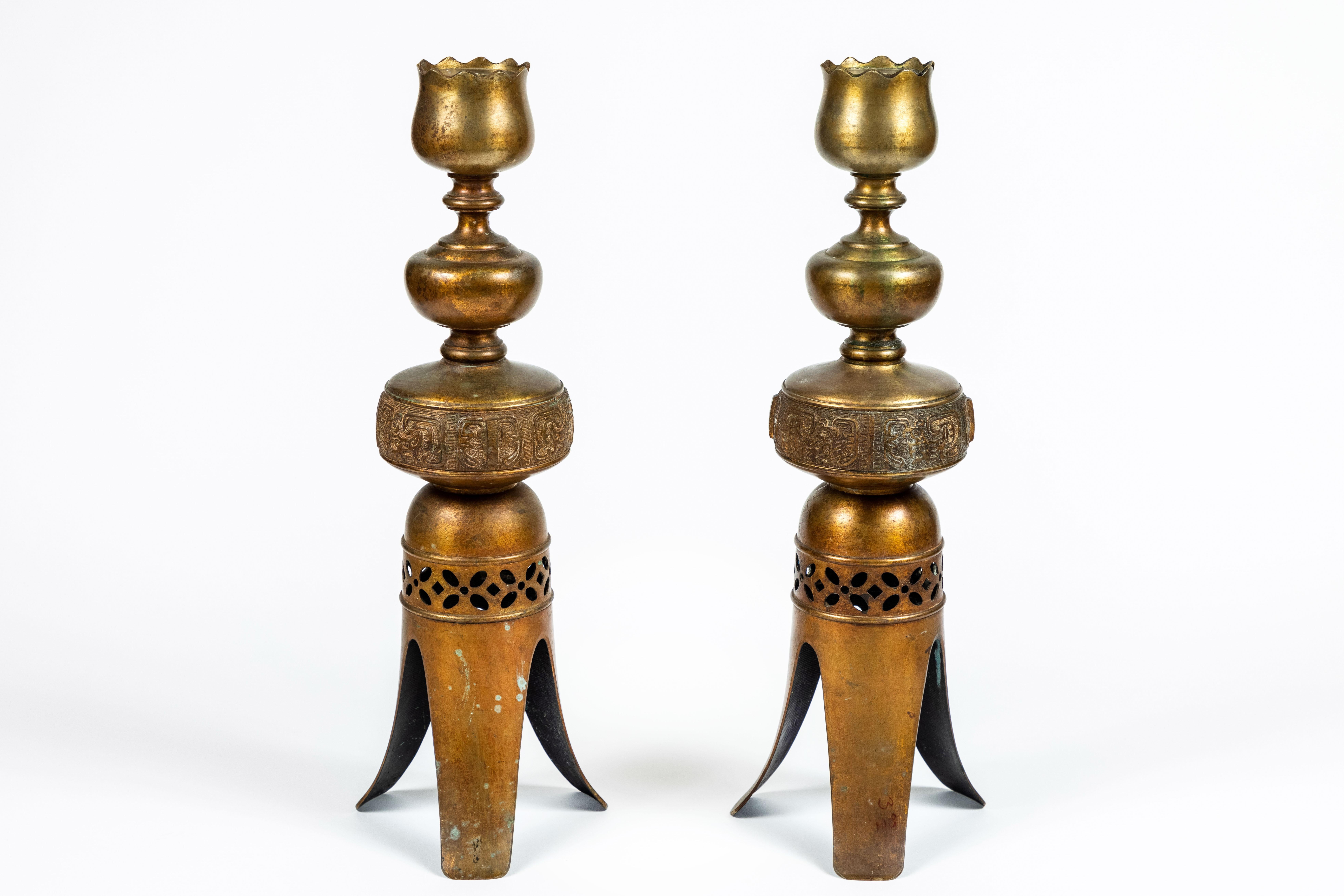 A pair of outstanding tall vintage intricately decorated metal candleholders with gold finish, 3-leg base with pierced design accent and possible Peruvian motif center detailing. Measures: 20.5