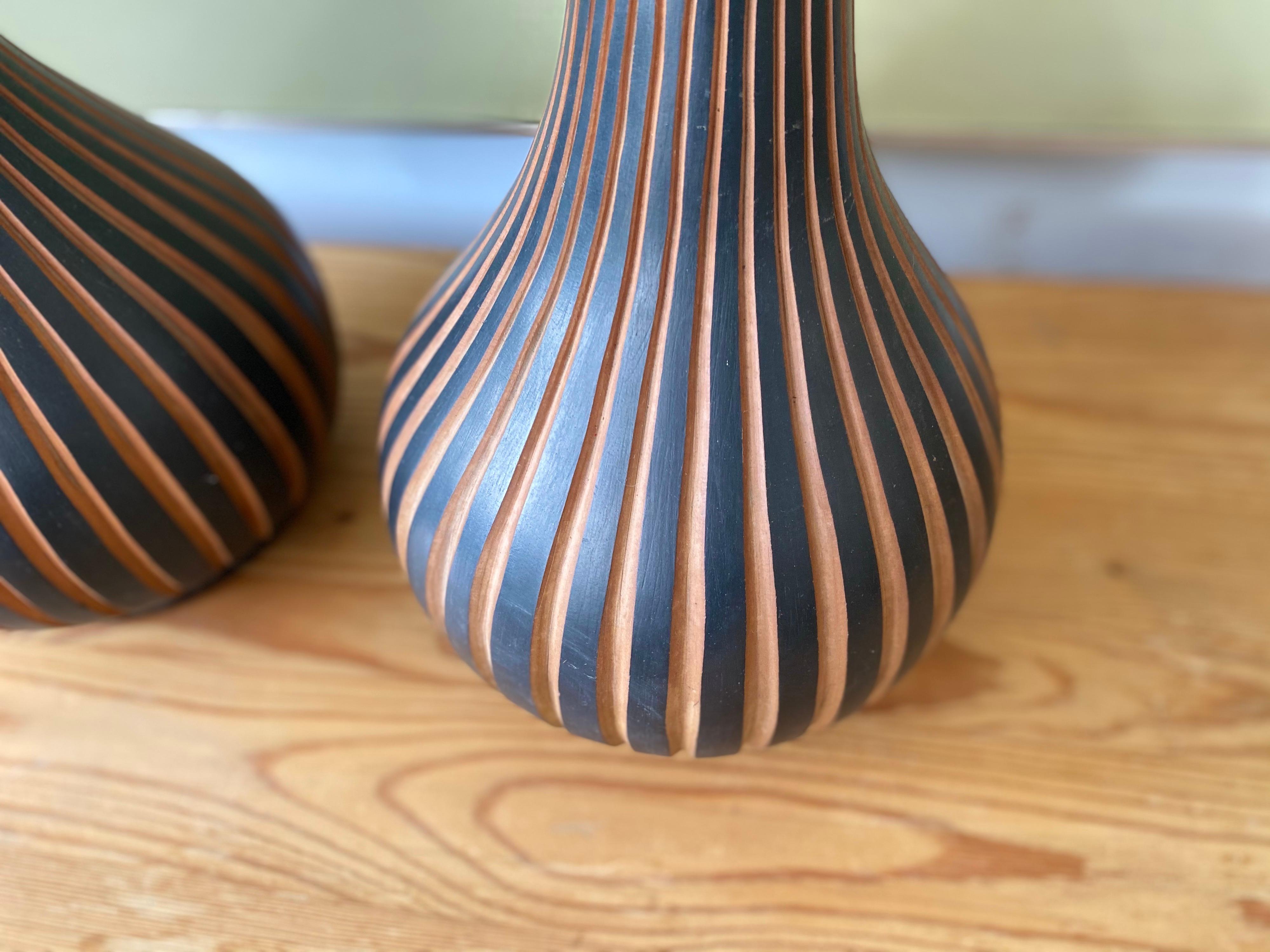 Pair of vintage Texcoco ceramic table lamps featuring a terracotta coloring, teardrop / bulbous form, and three-dimensional black matte vertical linear design. This unique sculptural lighting is in overall good condition and is sold as a set.