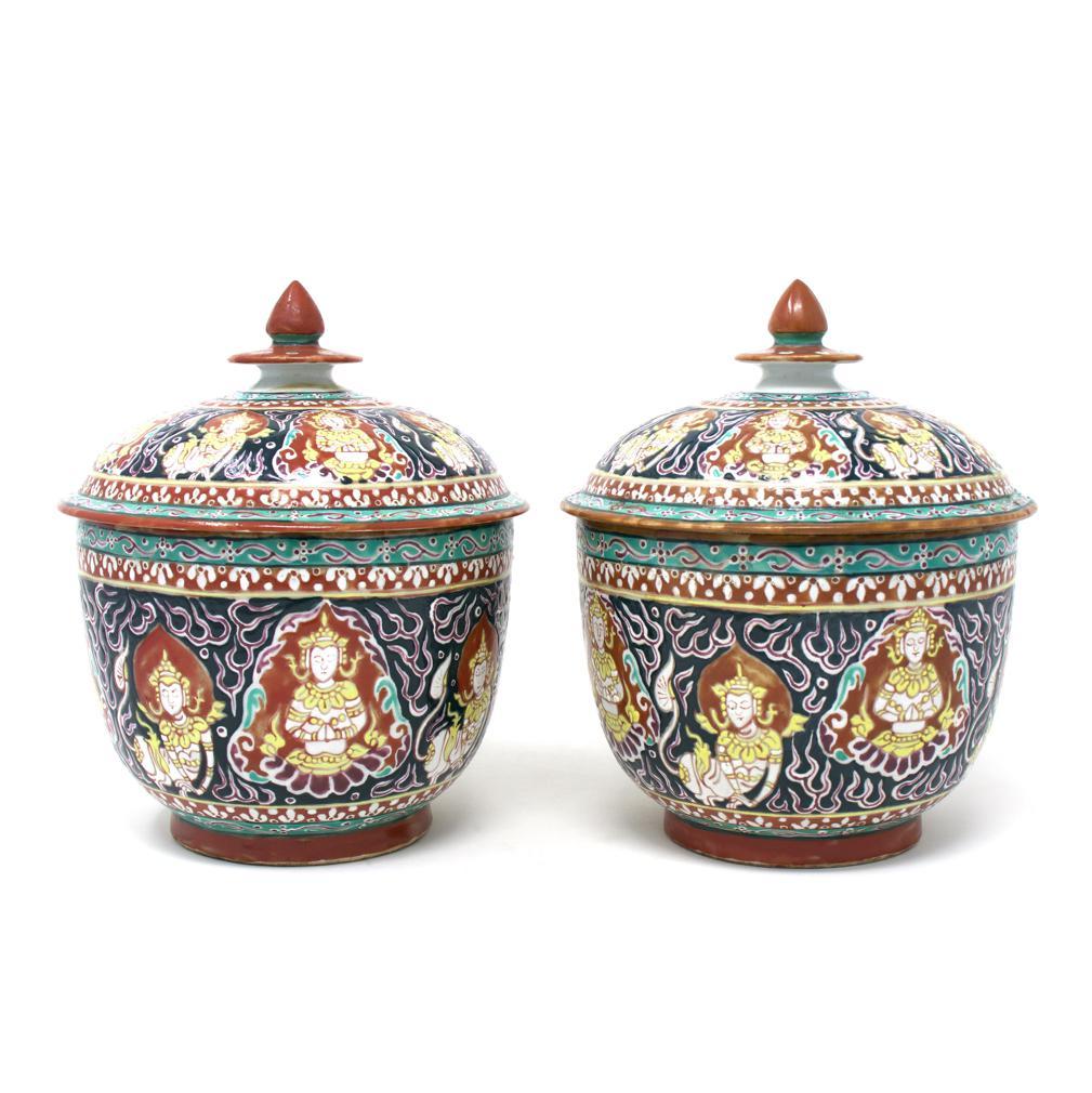 Pair of Vintage Thai Bencharong Lidded Jars, 20th century.
Bencharong enamel decoration with Buddhist imagery on a black background. This porcelain jar and lid form having a raised foot rim and lotus bud on a disk lid finial are richly decorated in