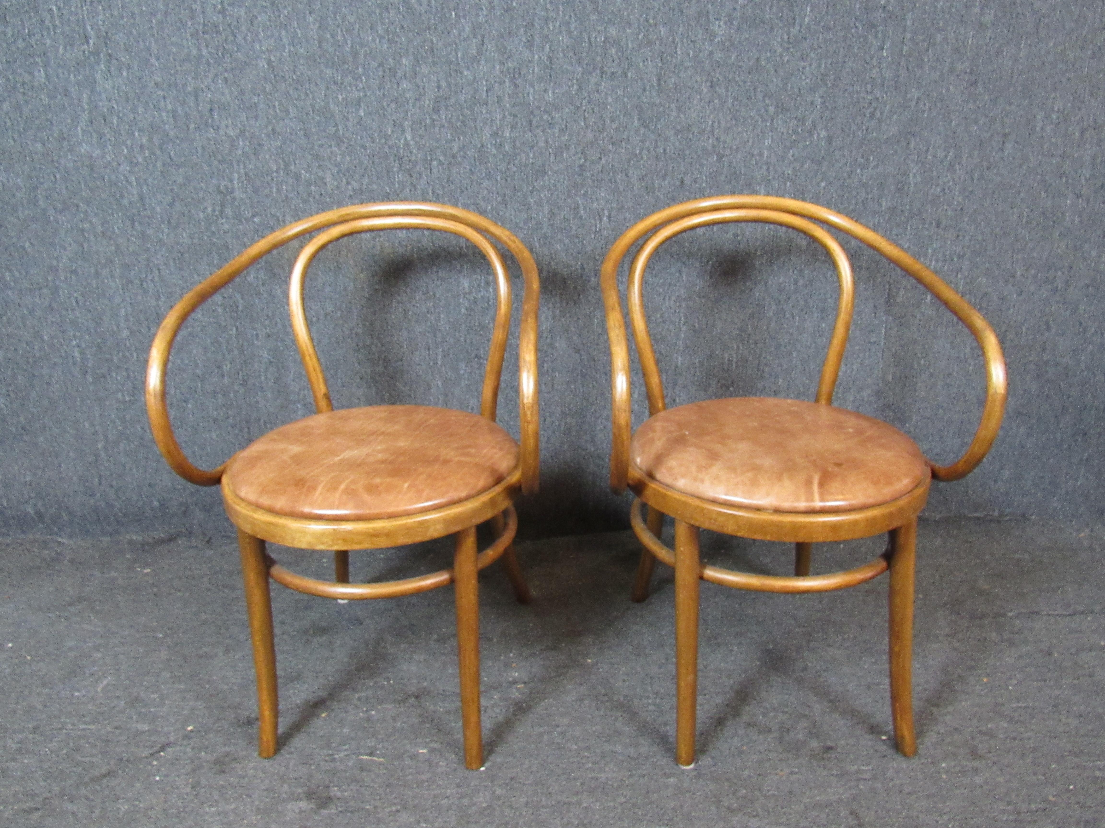 Terrific pair of bentwood dining chairs in the iconic Thonet design. Genuine craftsmanship provides study support that is sure to last for years to come. Beautiful wood grain and complimentary leather seats are sure to compliment a wide array of