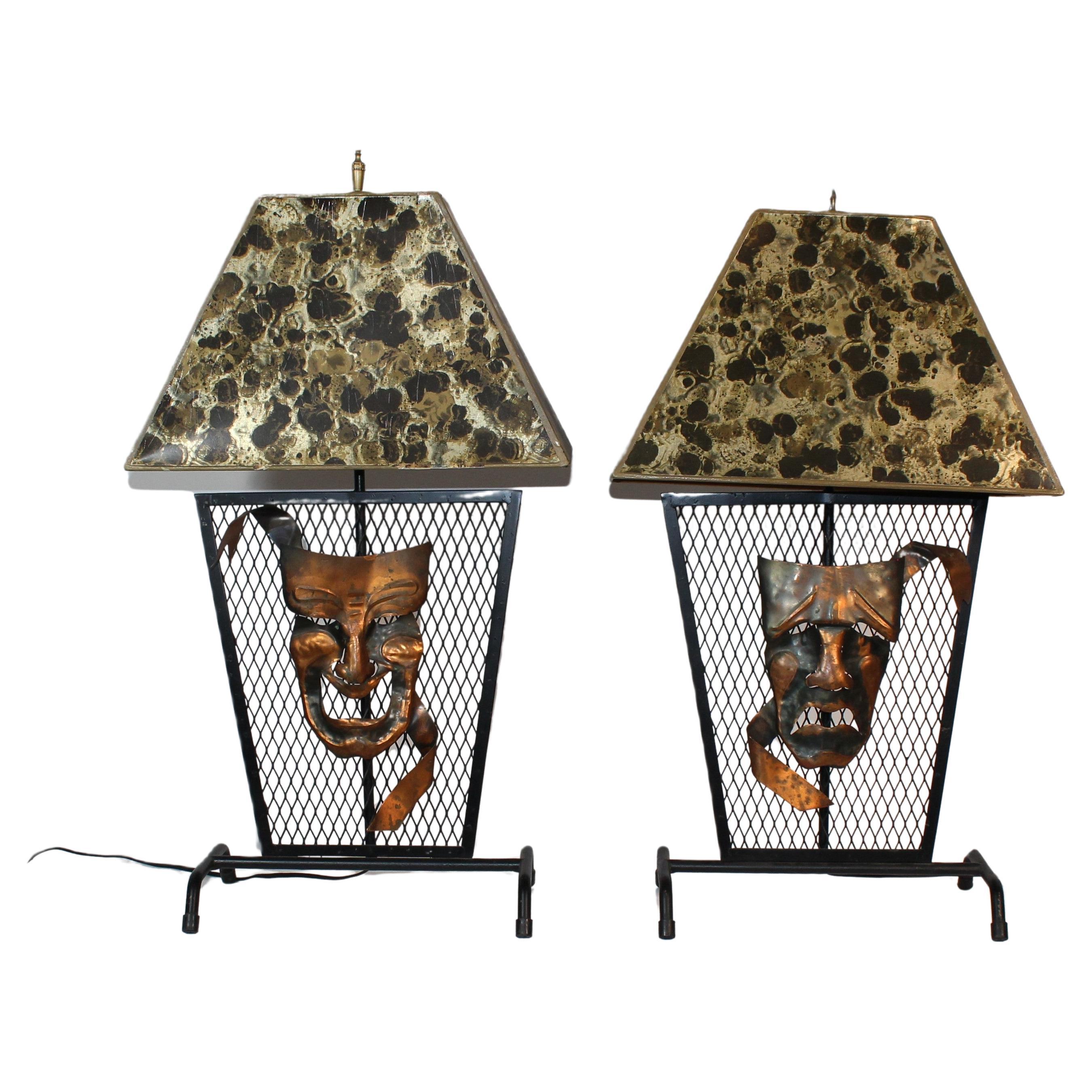 Paire de lampes vintage, sur treillis en fer. Avec des visages de tragédie et de comédie en métal plié sur le devant. Livré avec les magnifiques abat-jour en faux marbre. Socle d'ampoule standard