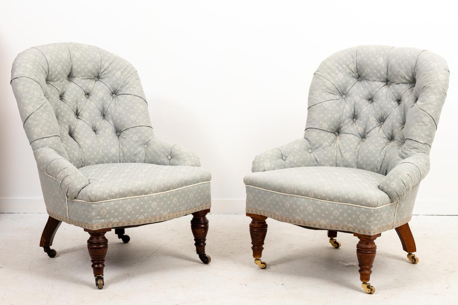 Circa 1980s pair of vintage tufted English style slipper chairs with turned legs on castors. Please note of wear consistent with age including minor fading.